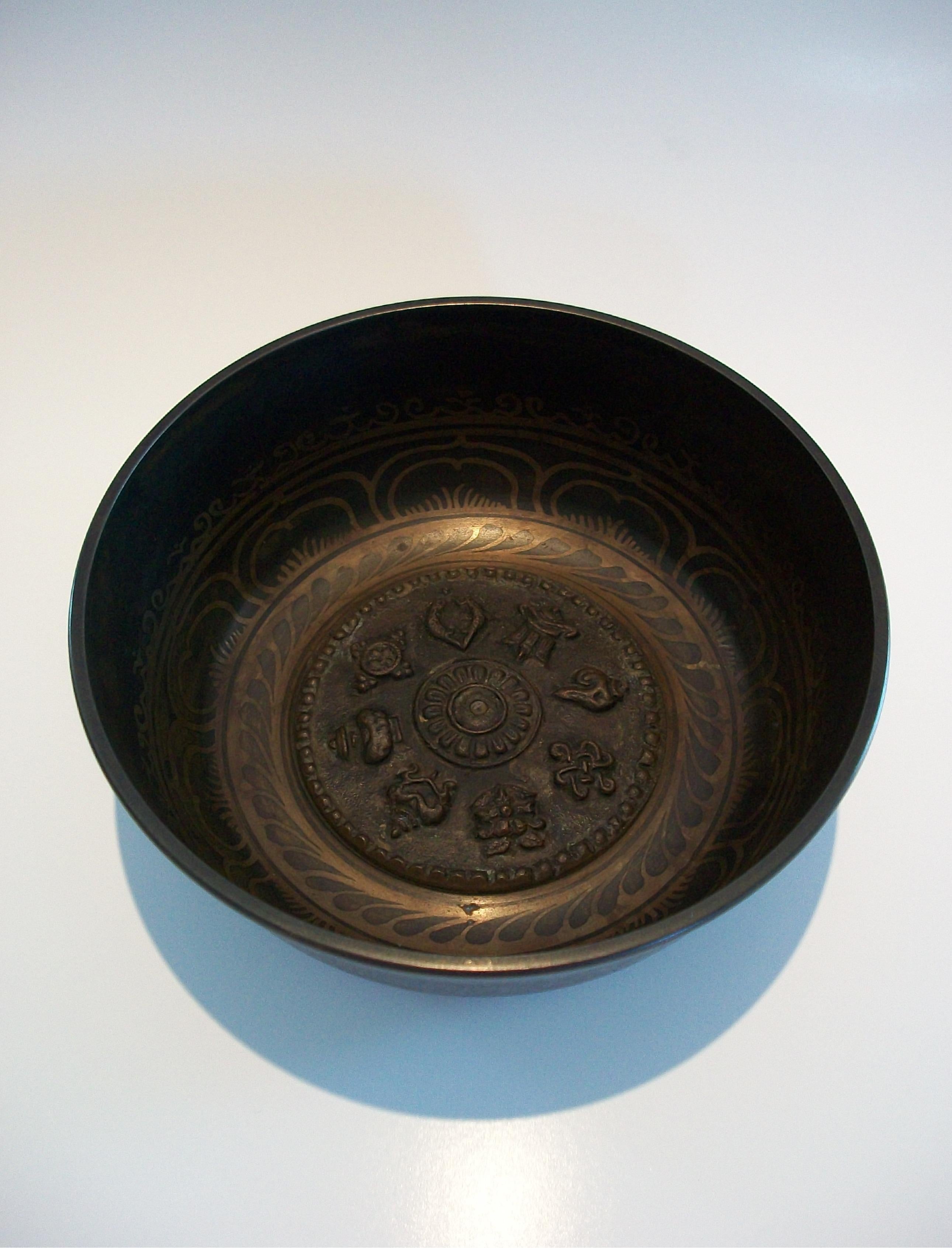 Vintage Tibetan Buddhist inlaid bronze singing bowl - featuring a cast central plaque with the eight auspicious symbols of Buddhism (golden fish, parasol, treasure vase, lotus flower, conch shell, infinite knot, wheel of Dharma and victory banner) -