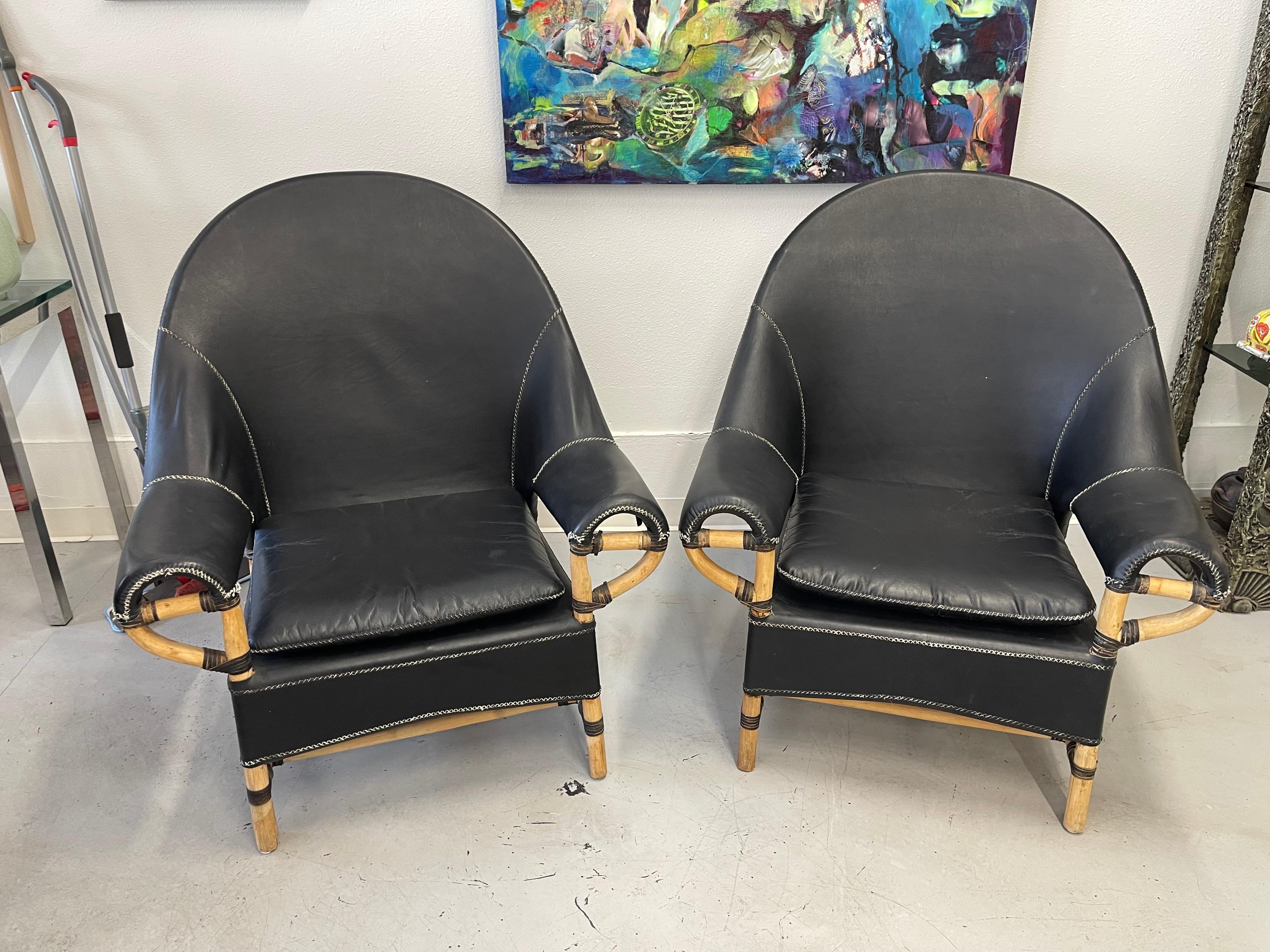 A great pair of Leather and Rattan chairs designed by Budji Layug. They have a tag on the underside. These have hide wrappings similar to Mcguire. These are made well with thick leather. These chairs are in vintage condition, with charming wear and