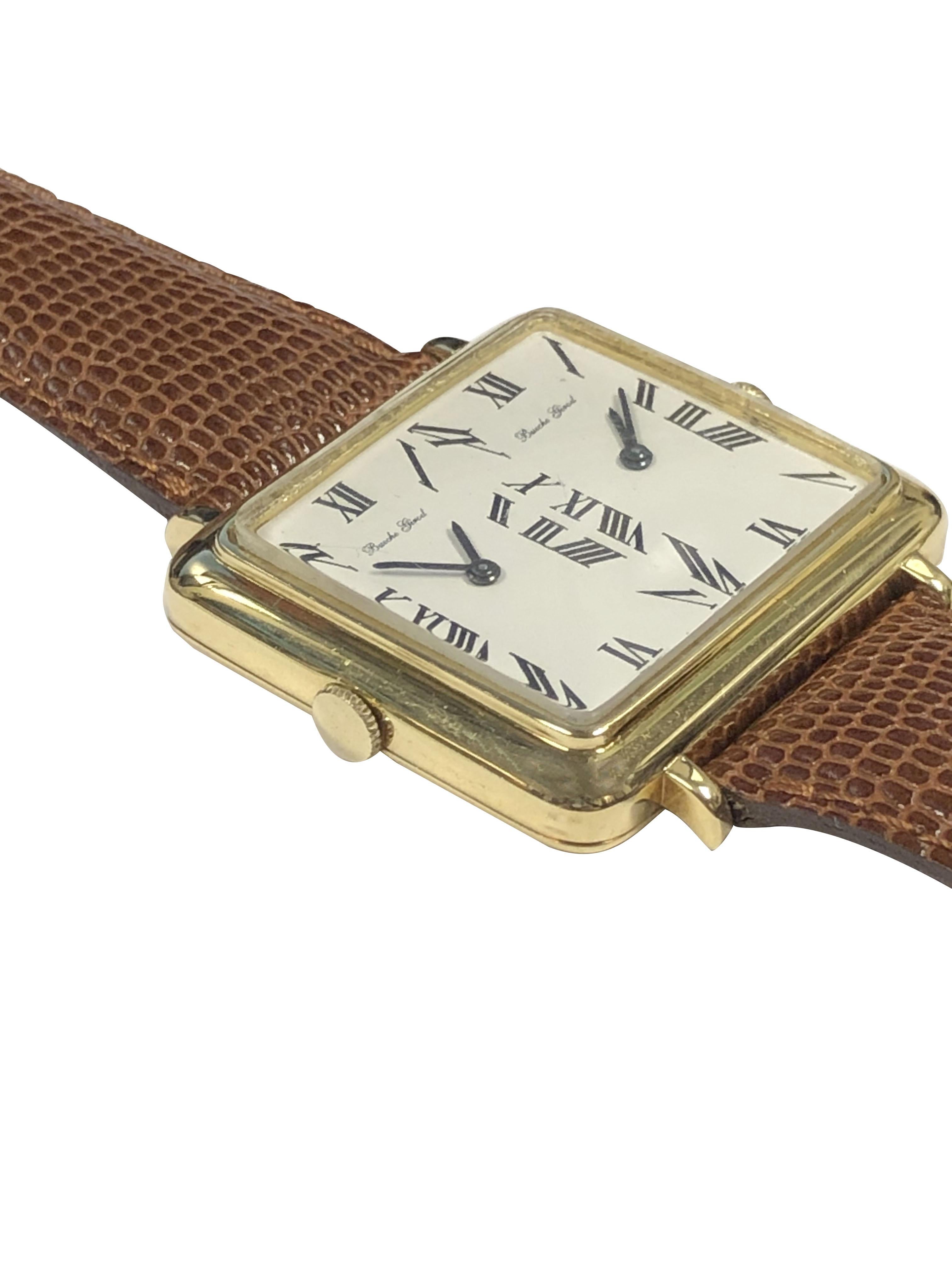 Circa 1970s Large and Impressive Bueche Girod 2 Time Zone Wrist Watch, 35 X 31 M.M. 18k Yellow Gold 2 Piece case. Having 2 individual 17 Jewel mechanical, manual wind movements. White Enamel Dial with Black Roman numerals. New Brown Lizard Strap
