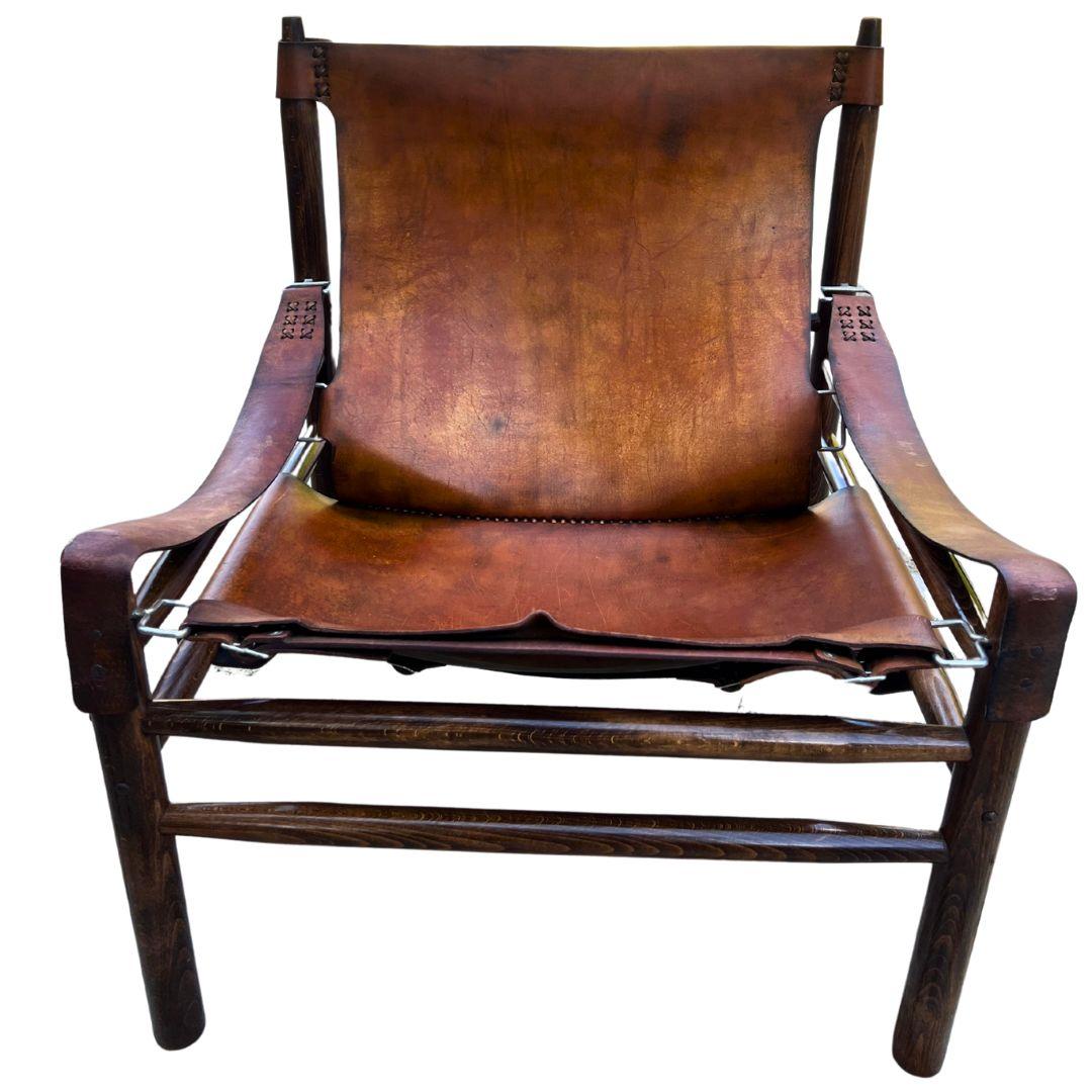 Questa poltrona in stile Safari degli anni '70 ha un'atmosfera classica, grazie alla ricca pelle di bufalo e al rovere massiccio. La pelle è invecchiata benissimo e il legno è ancora in ottima forma.

Il suo design semplice e rilassato si adatta