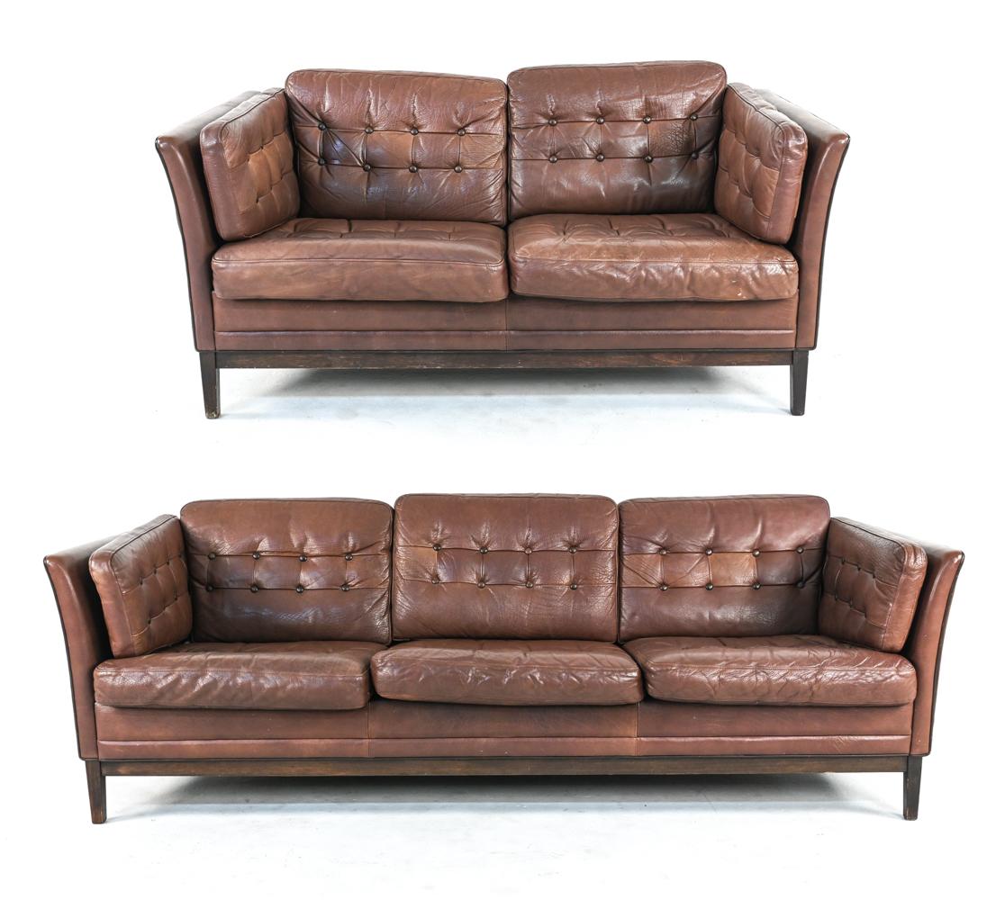 This fabulous living room suite consists of a three-seat sofa and two-seat settee with removable tufted cushions, fully upholstered in fine chocolate brown buffalo leather. Pair them with a sheepskin rug and sculptural drum-style end table for a