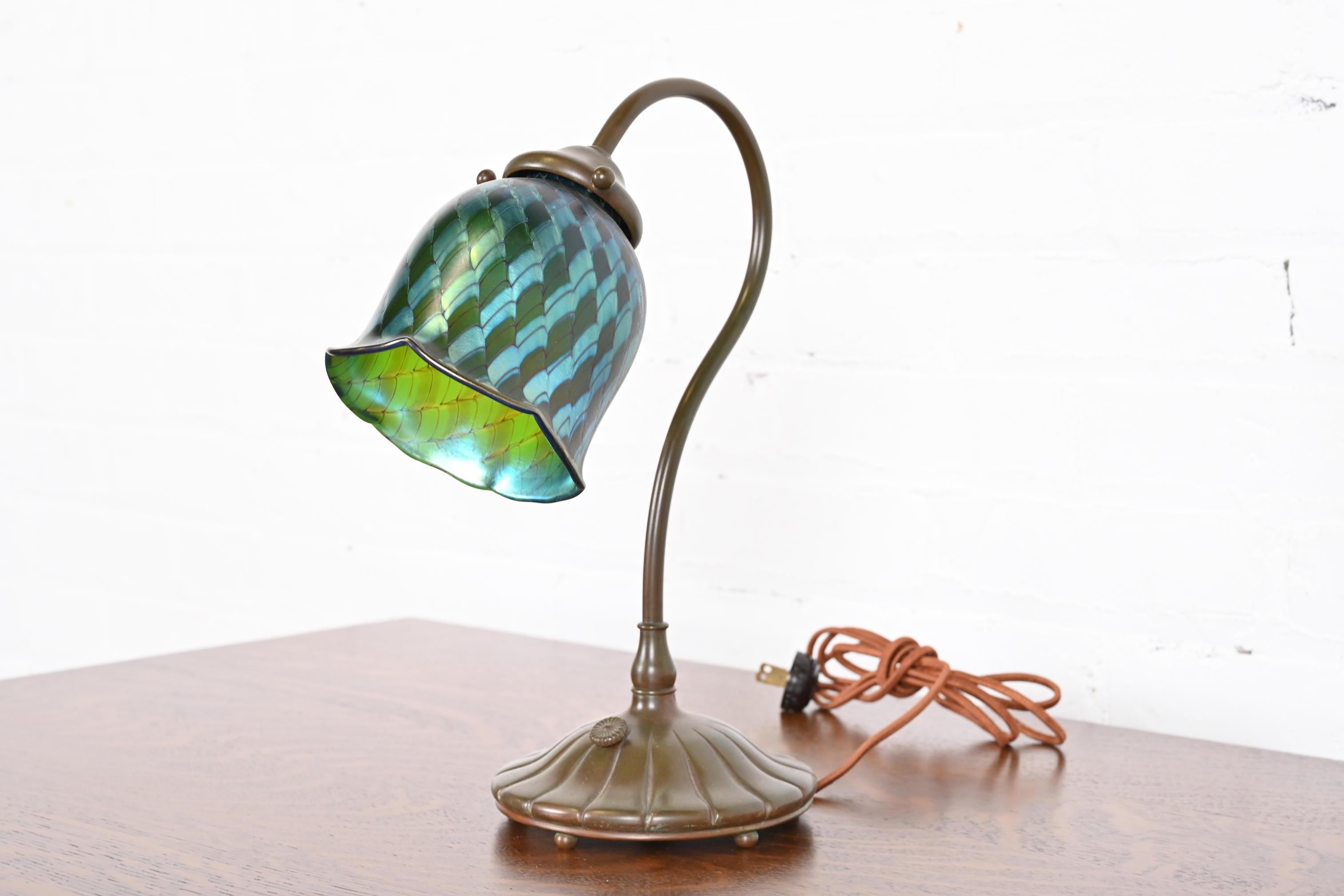An outstanding Arts & Crafts or Art Deco period desk lamp

In the manner of Tiffany Studios

By Buffalo Studios of Pasadena, CA

USA, Circa 1910

Bronze, with beautiful green and blue iridescent favrile glass shade.

Measures: 10