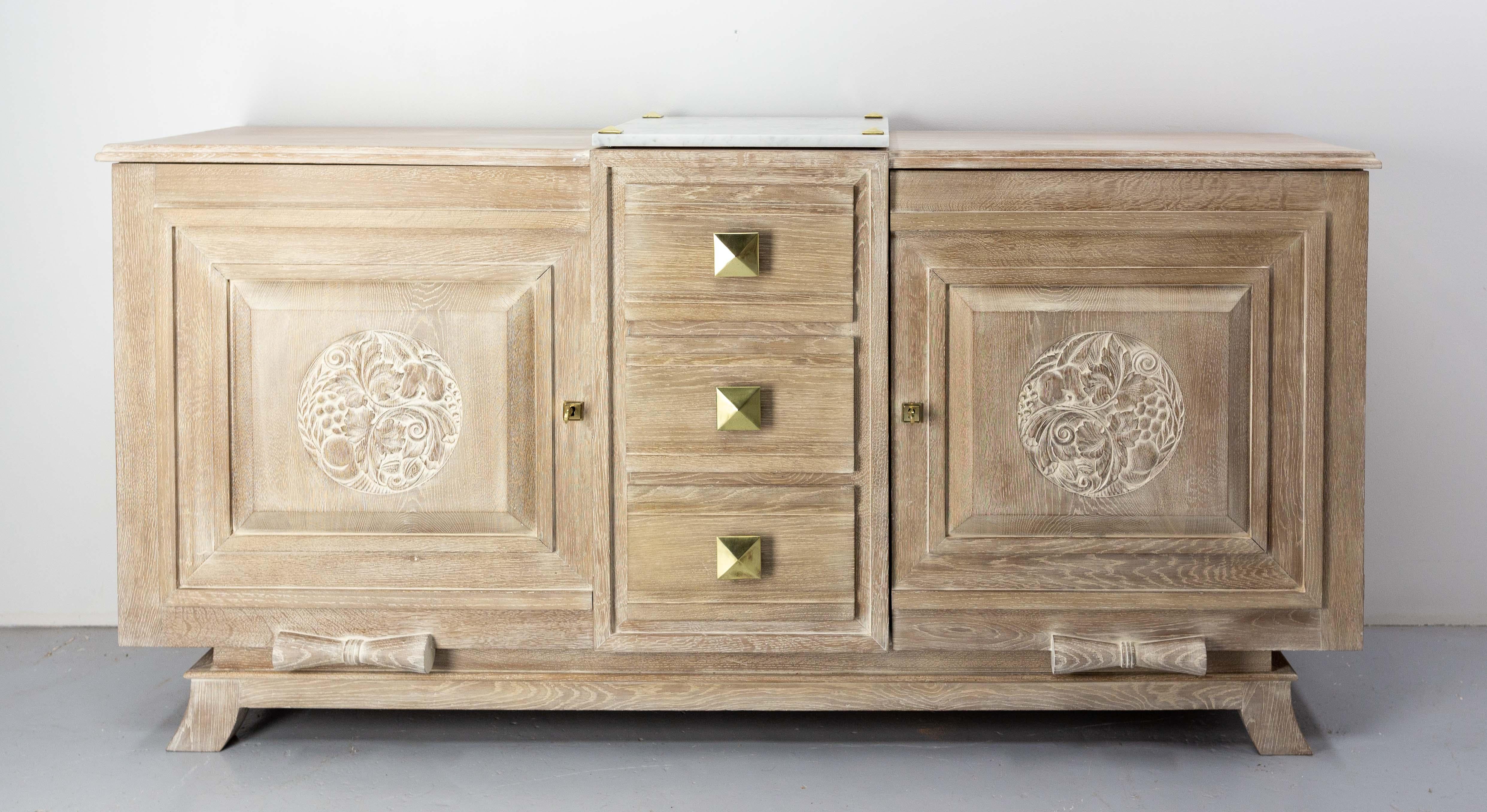 Art Déco French buffet cerused oak, marble top and brass.
The floral bas-reliefs are highlighted by the white ceruse.
Made circa 1930
Two doors and three drawers.
Completely redone finishes.
Two traces of an old buffet hut are visible on the
