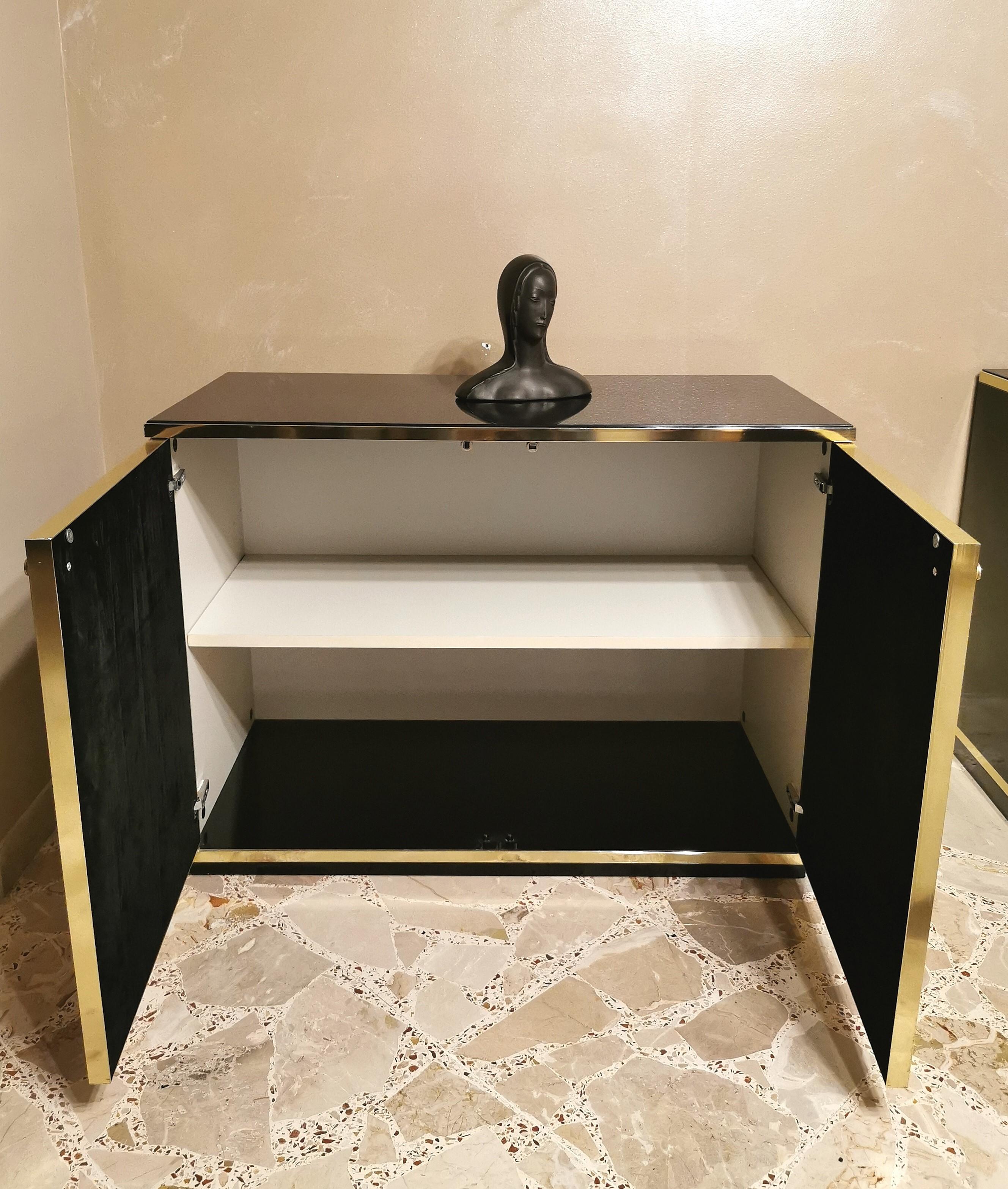 Elegant buffet designed by the Italian designer Renato Zevi in the 70s. The buffet has a black lacquered wooden structure, a dark glass top, 2 bronze mirrored glass doors with black suede inside and 1 wooden shelf. Finishes in gilded aluminum and
