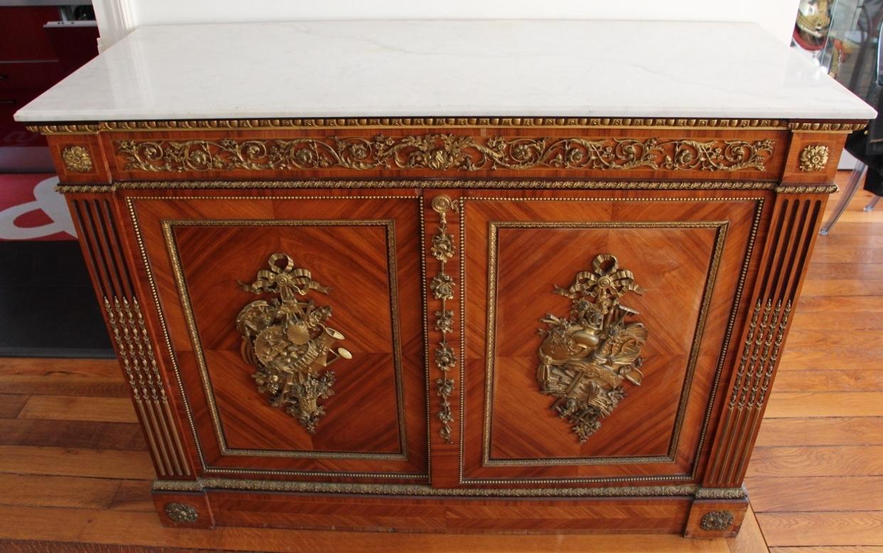 Support cabinet in rosewood opening to a drawer and two doors decorated with trophies of agrarian instruments revealing four drawers, the fluting and asparagus posts, the belt decorated with foliage foliage; Above white marble. Guillaume Grohé