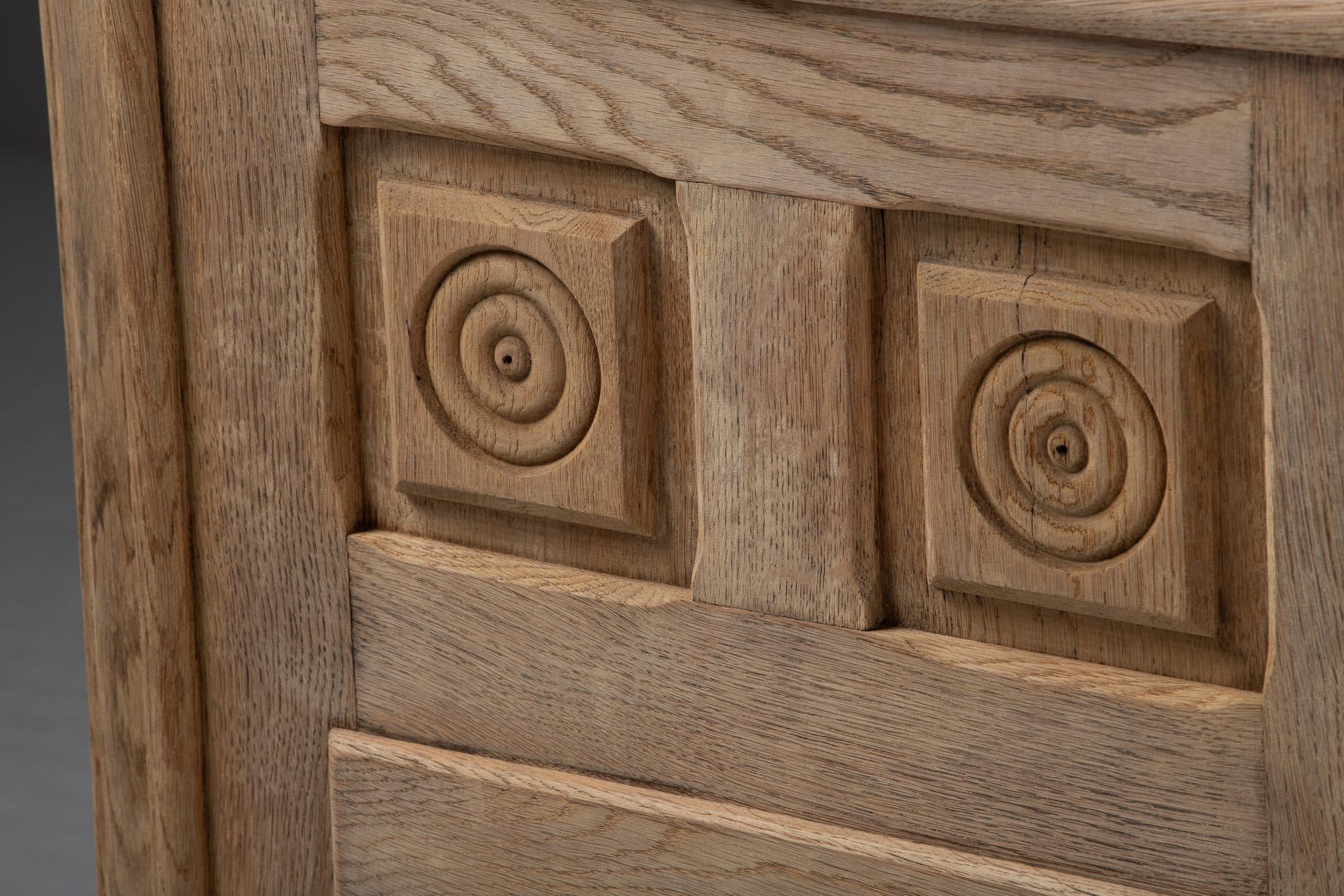 This French buffet unfolds like a carved hymn to symmetry and craft. Its tripartite façade is marked by a rhythmic procession of concentric rosettes, each hand-carved with meditative precision into recessed square panels. The repetition of these