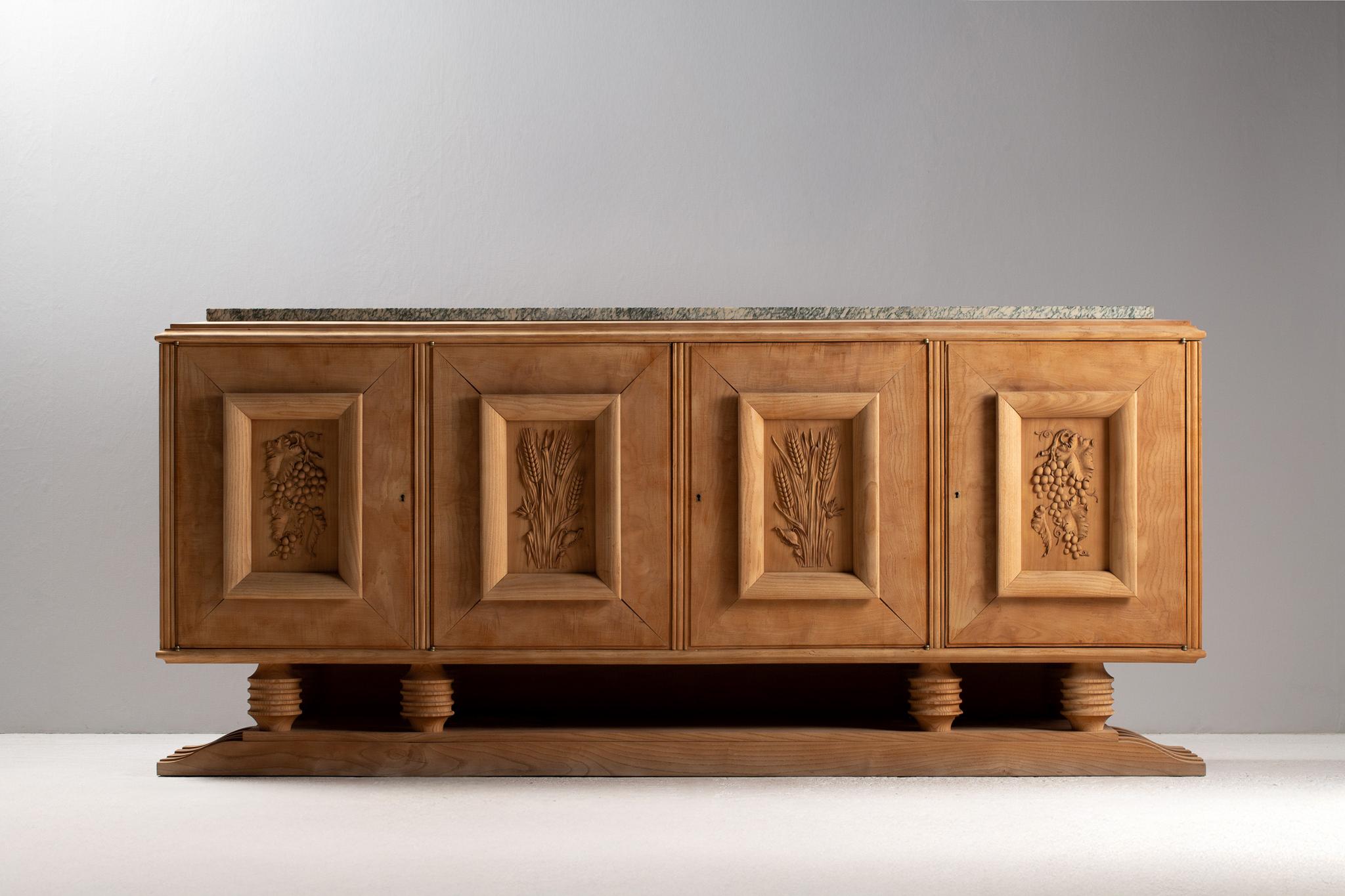 Buffet in Oak intagliato con piano in marmo, Francia, anni '50

La facciata di questo buffet monumentale si dispiega come un fregio pastorale: quattro porte a pannelli, ciascuna incorniciata in rilievo piramidale, recano emblemi intagliati a mano di