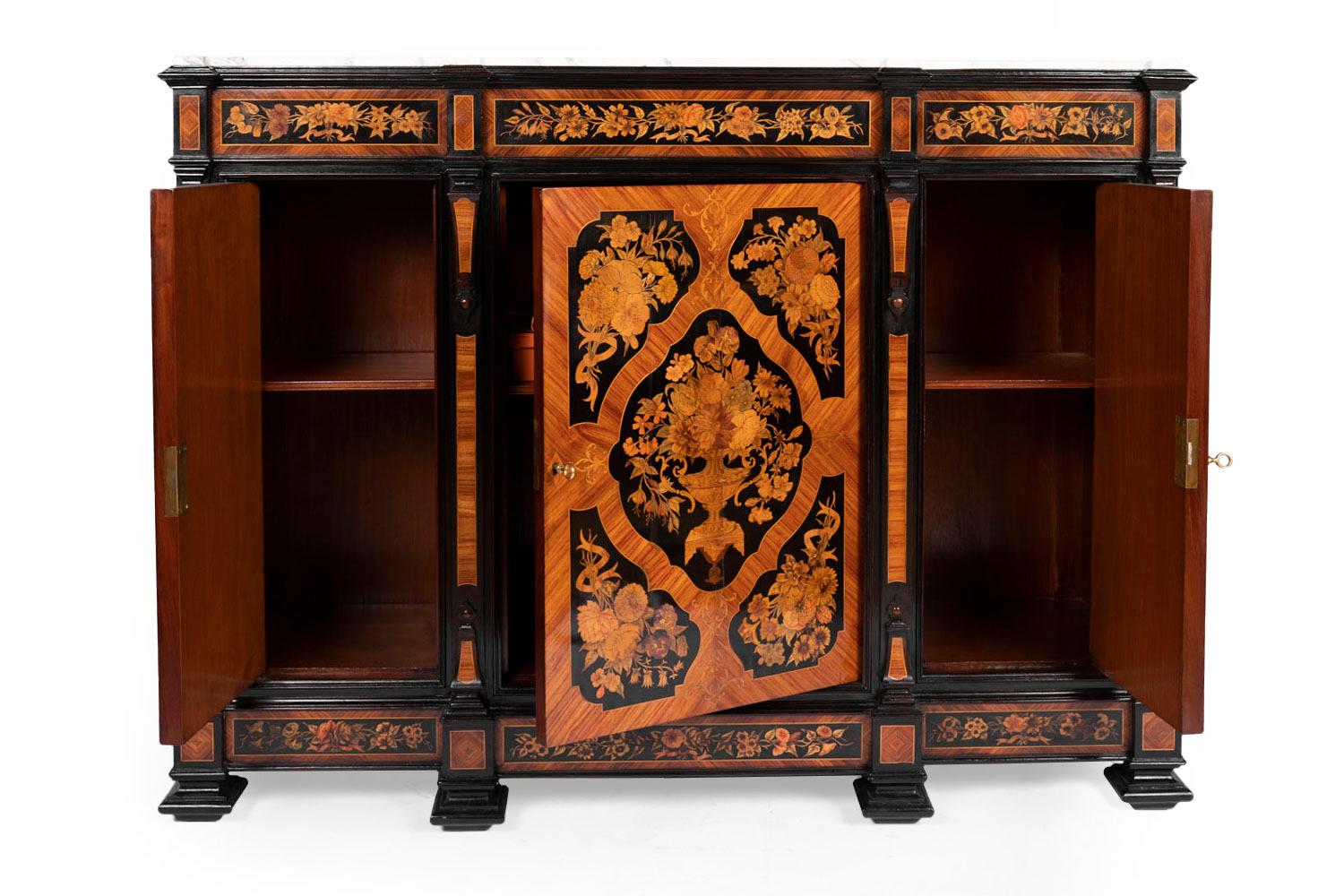 Buffet in floral marquetry on a black lacquered wood. Breakfront buffet with projected uprights, opening by three door leaves, each one displaying a compartiment with a shelf. It stands on six square legs : four front moulded ones and two back ones.