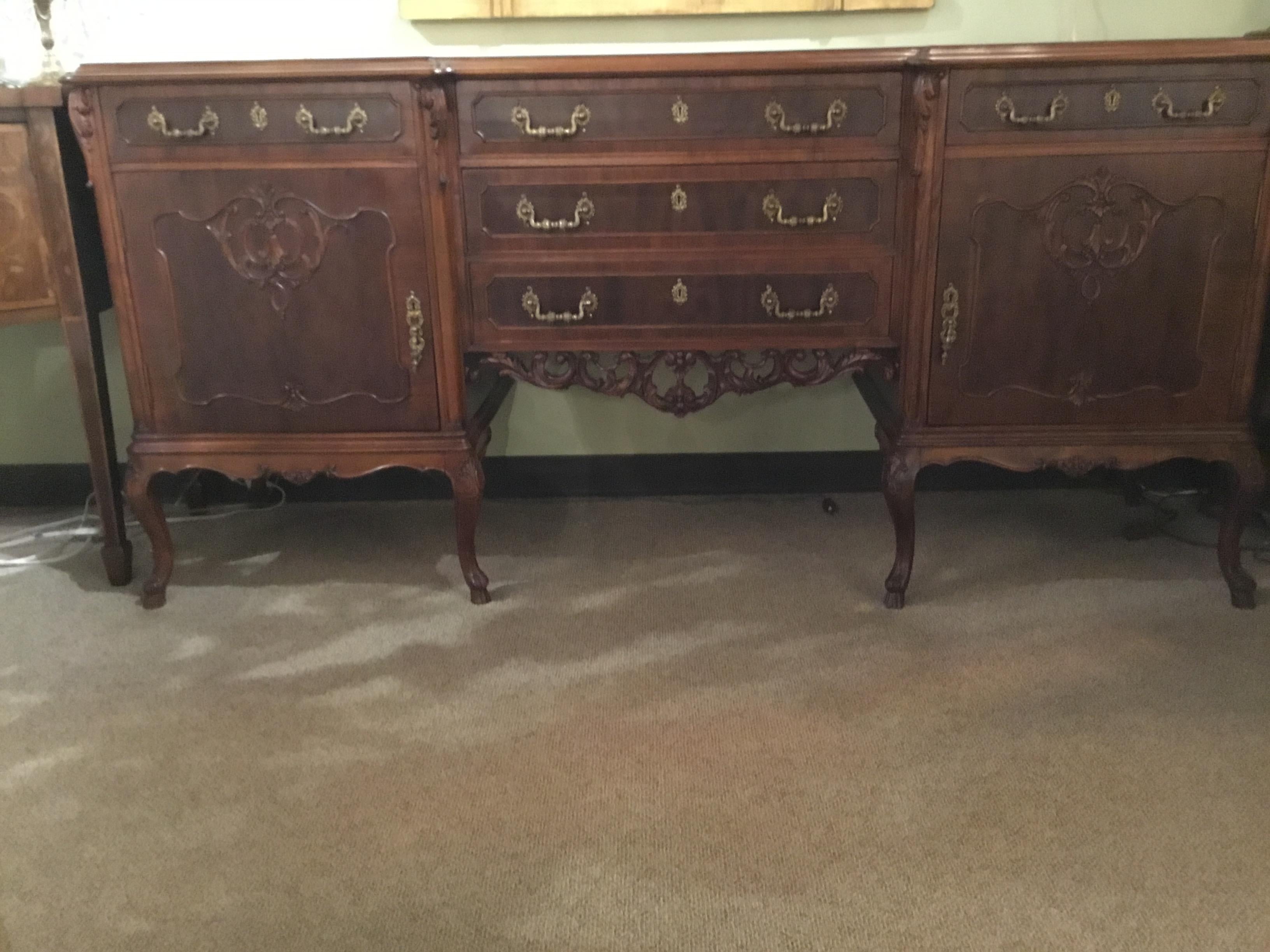 Handsome buffet with great storage. Two doors that open on each side
with three drawers down the center of the piece. Carved apron at the
center. Curved leg ending in a hoof foot.