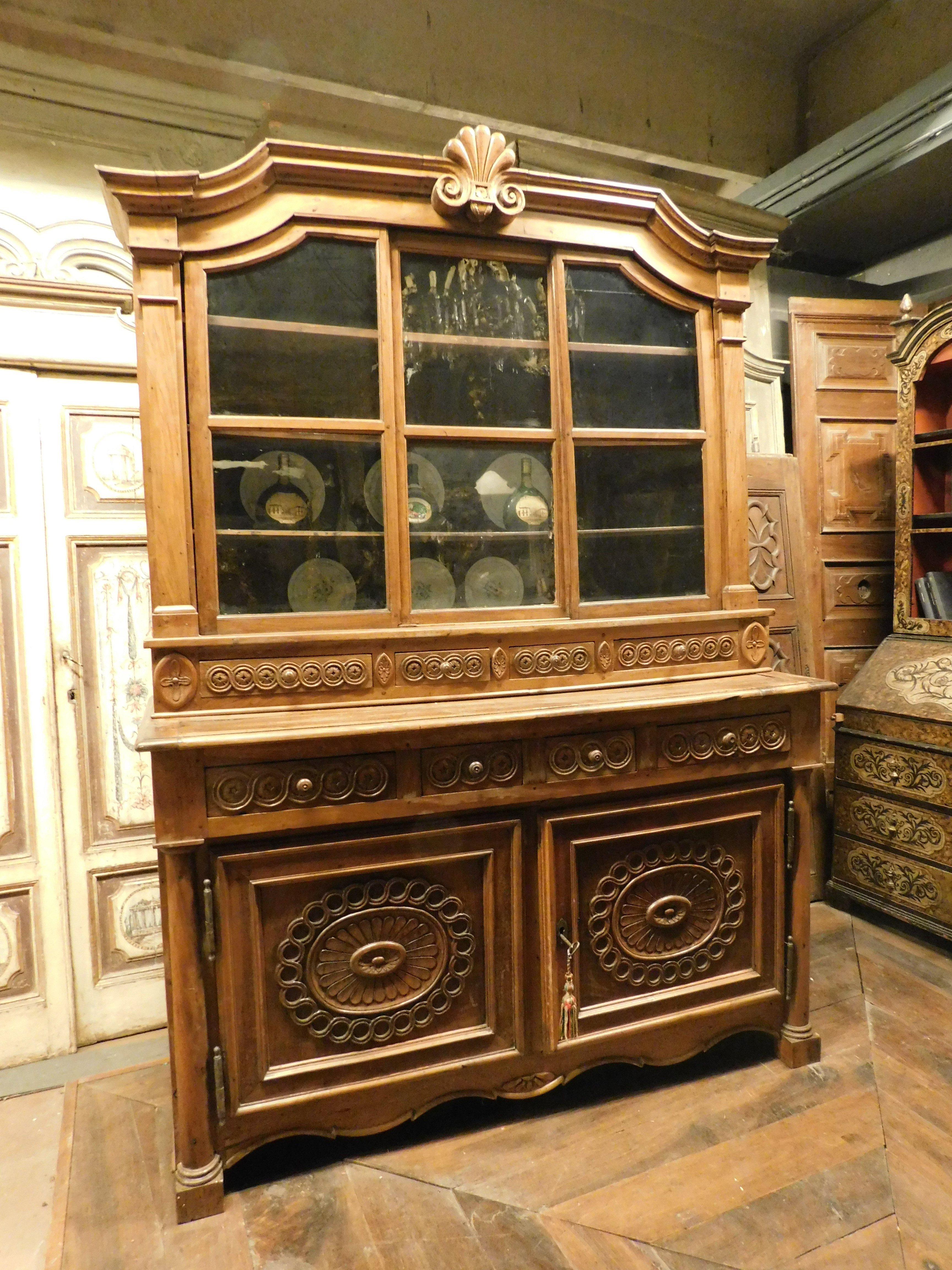 Antique and precious Buffet sideboard, built in richly carved walnut with upper glass doors. The base has two richly carved doors and four drawers. The shelf is characterized by three sliding doors with glass and shelves inside. At the base of the