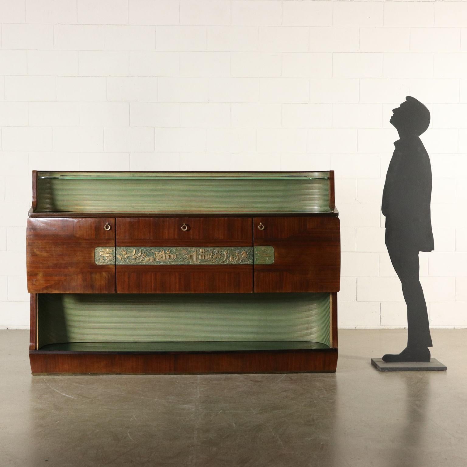 Buffet and bar compartment with drop-leaf door. Wood veneer, carved lacquered ornaments, glass tops. Designed for Consorzio Esposizione Mobili Cantù. Manufactured in Italy, 1950s.