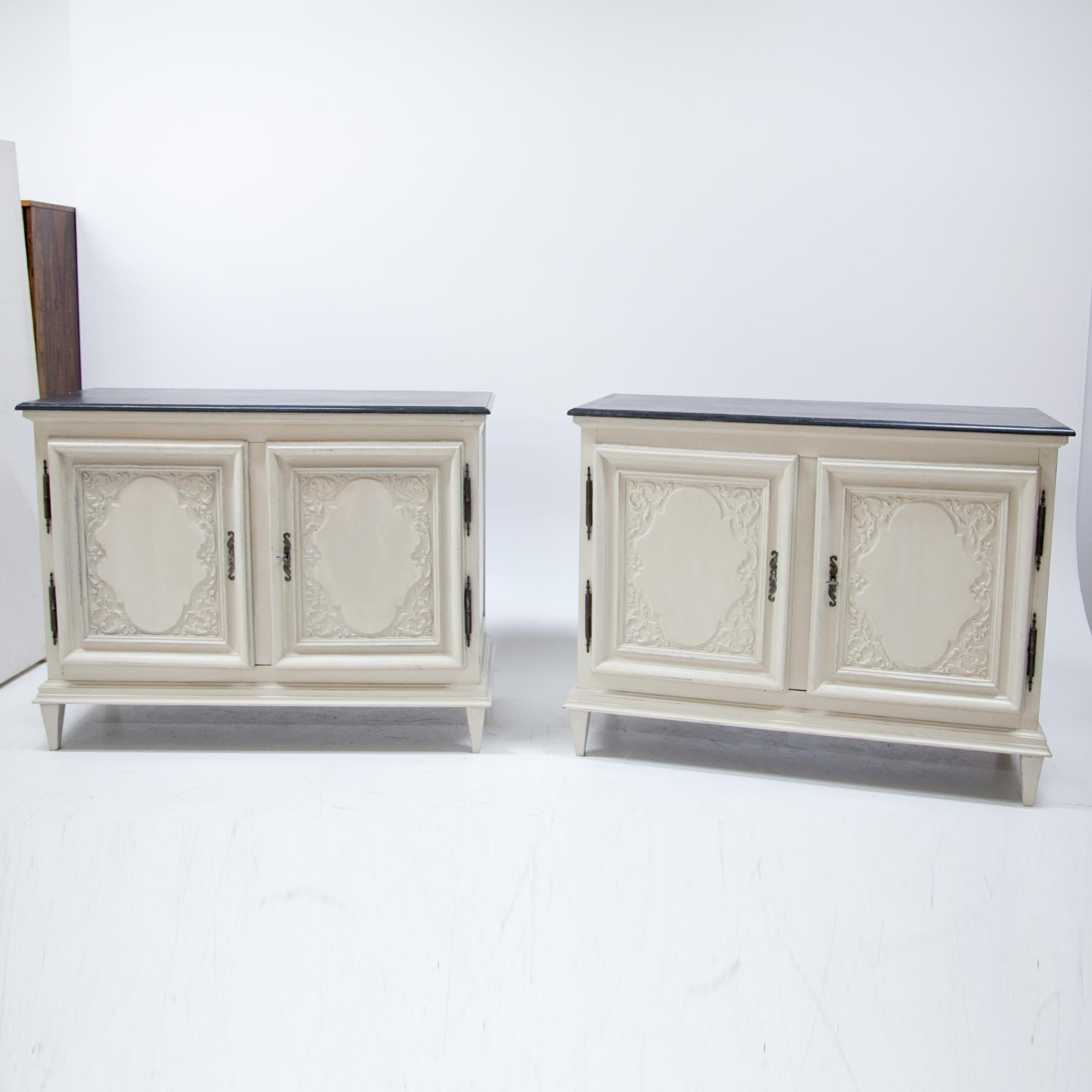 Pair of two-doored buffets out of solid walnut, standing on tapered legs. The buffets are decorated with profiled edges and fillings with carved vines and wavy medallions. The crème and grey paint is new and has a slight distressed look to it. Legs