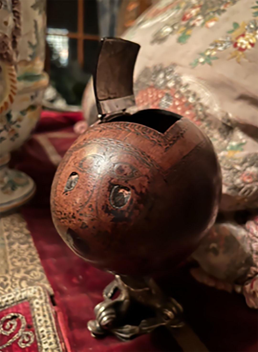 A Bugbear coconut tea caddy mounted on a silver dolphin base. Bugbear coconuts were carved by sailors on long voyages in the 18th and early 19th centuries.