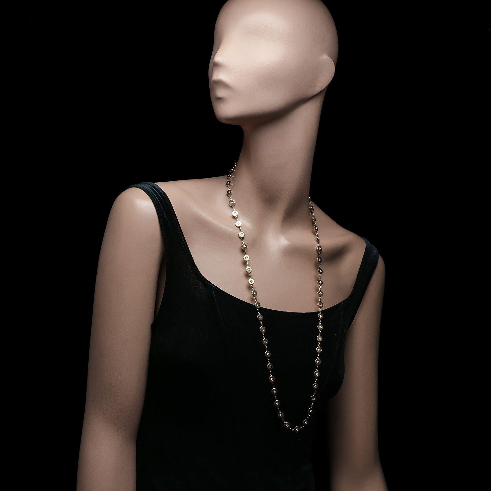 A beautiful gold and diamond long sautoir necklace by Bulgari c.1990s, the 32” necklace formed of fifty three uniform chunky round discs in 18ct yellow gold, joined by short chain link sections, each disc set to the centre with a single round