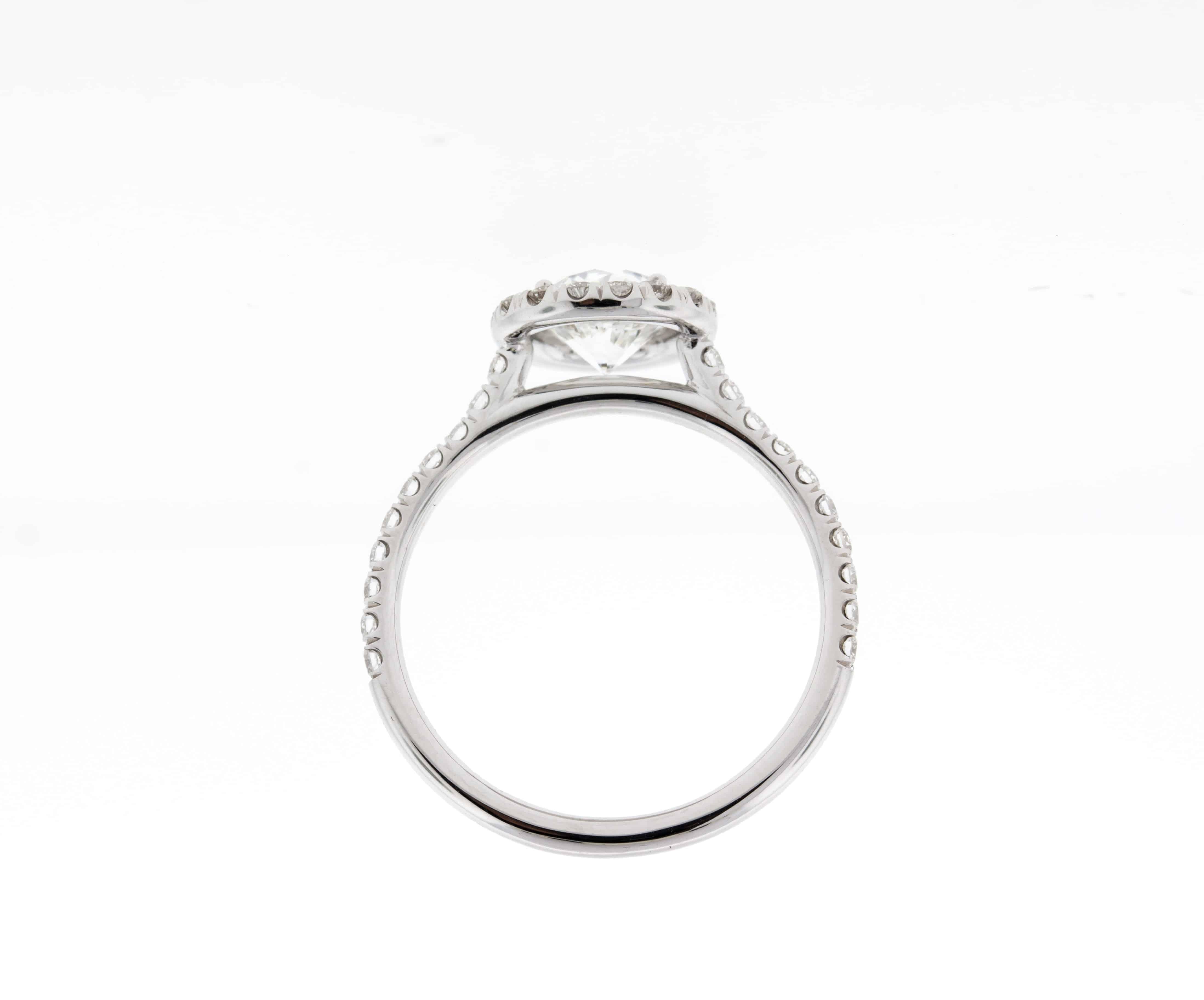 This custom diamond engagement ring features a round diamond with a built-in (cathedral style) setting with a matching diamond halo and u-pave diamonds 3/4 of the way down the band, this engagement ring can be made in any color gold or in platinum.