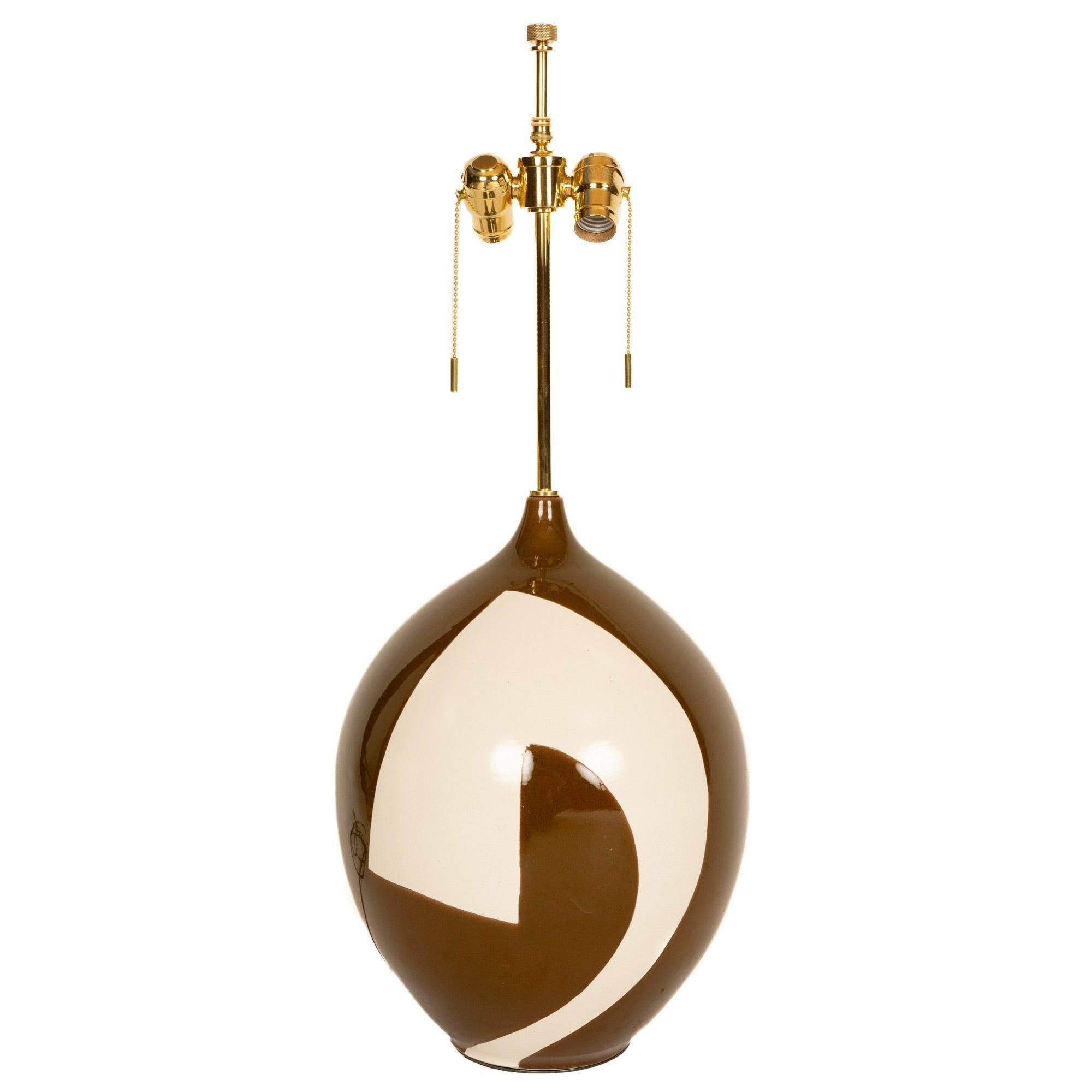 A bulb shaped ceramic table lamp in an earthy green/brown and white high gloss glaze with an abstract design throughout.