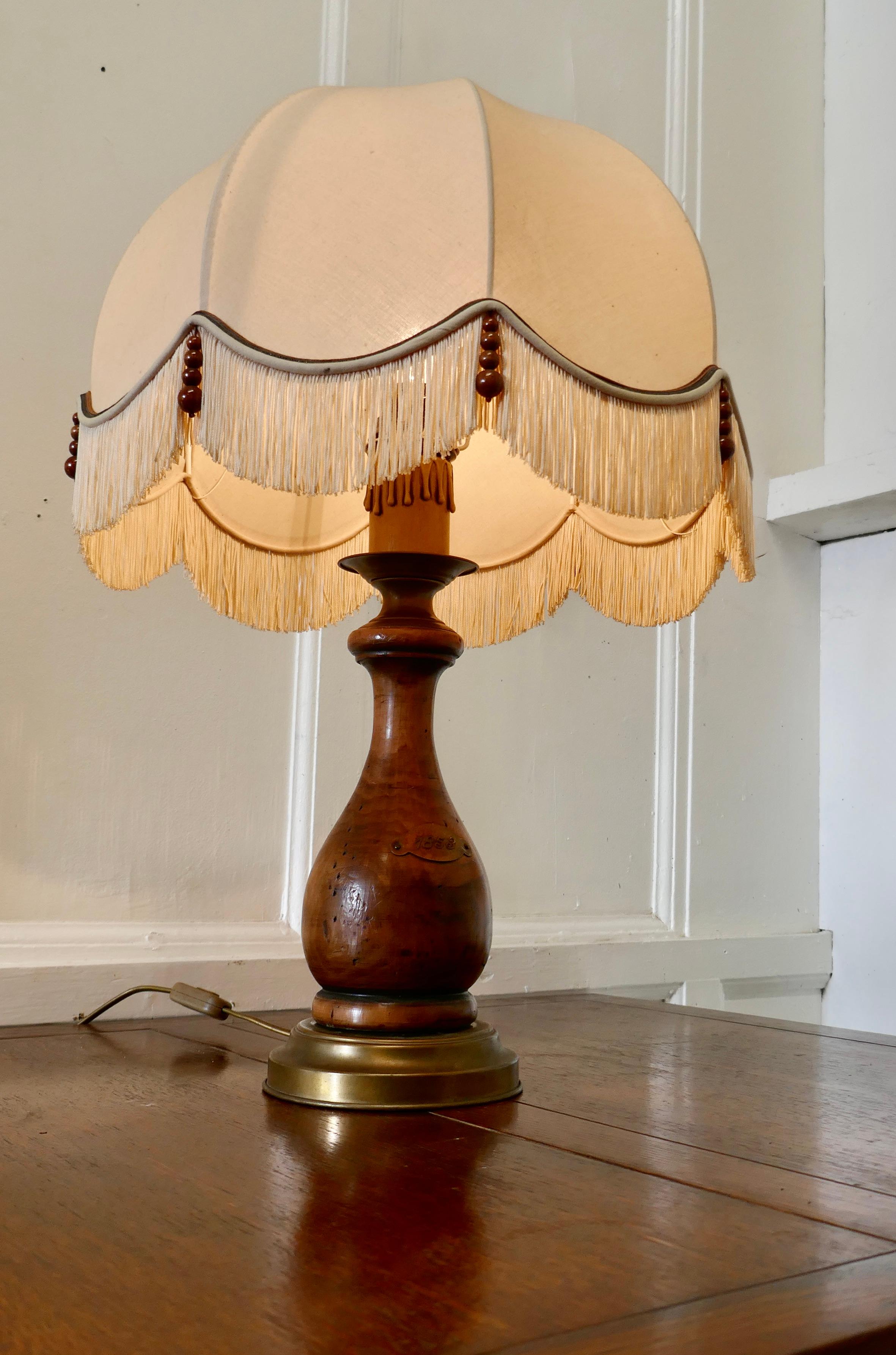 Bulbous wood French table lamp with dome lampshade

The lamp has a large turned wood base which is topped off with a superb large dome lampshade in linen decorated with beads, it has a brass plaque stamped 1853
The lamp and shade are in good used