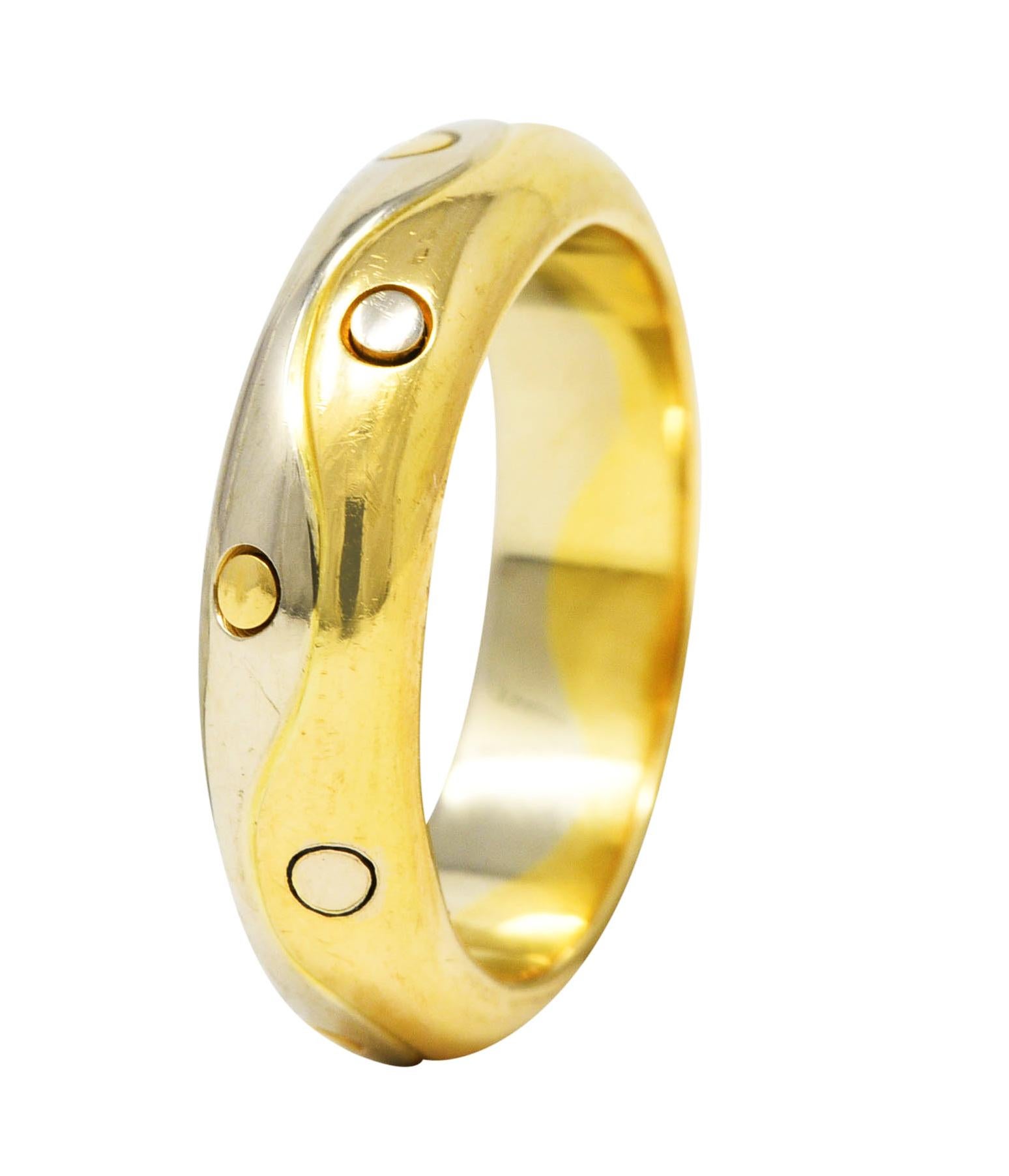 Band ring is designed as yellow and white gold halves. With grooved wave motif median and spots of alternating gold color. Stamped 750 for 18 karat gold. Fully signed Bvlgari, Made in Italy. Circa: 1990's from the Onda collection. Ring size: 6 and