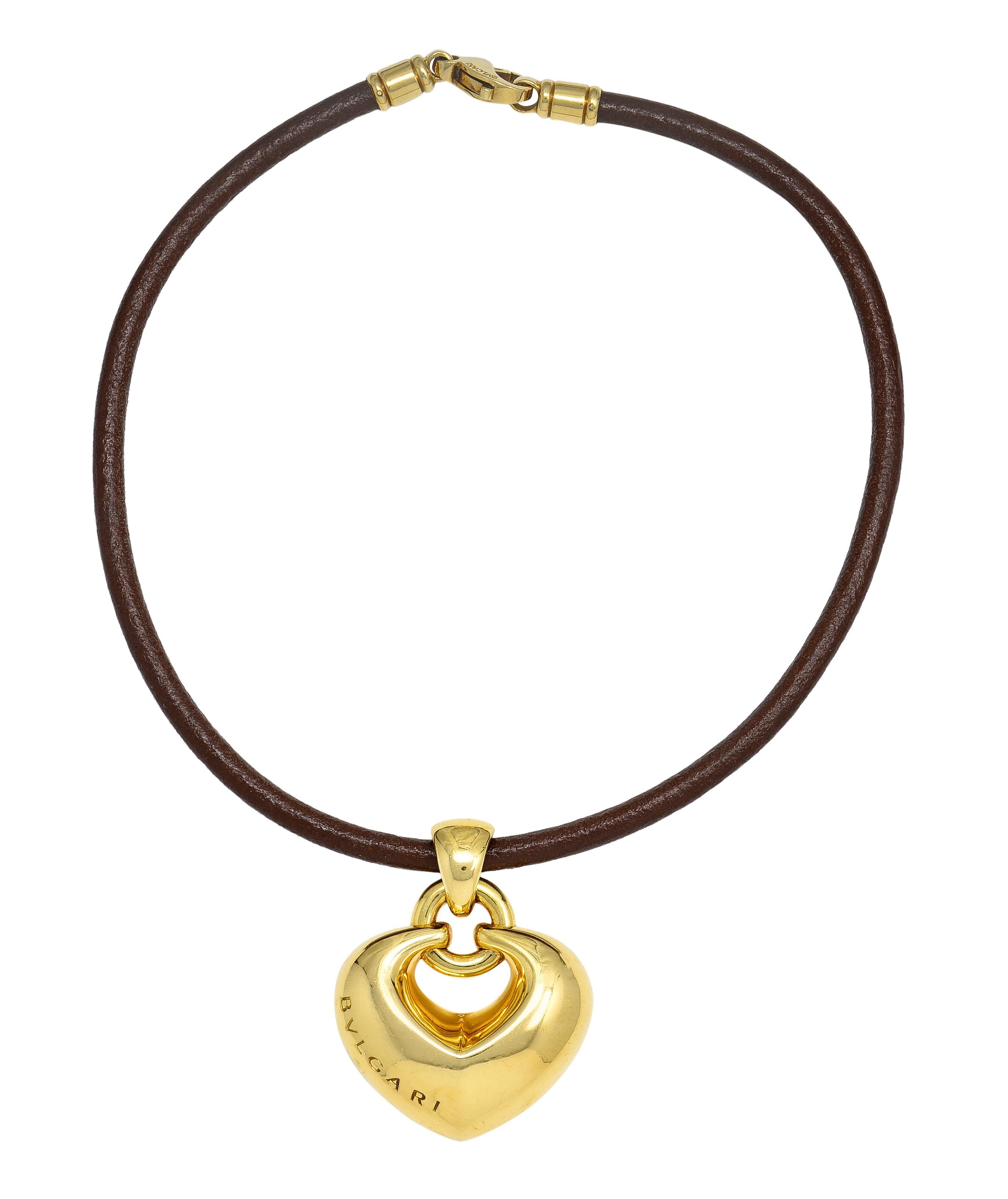Besteht aus einer hellbraunen Lederschnur, an der ein stilisierter Herzanhänger hängt. Gepufft mit feiner, facettierter Oberfläche und der Aufschrift 'Bvlgari'. Aufgehängt an einem Ballen mit Sprungring - mit hochglanzpolierter Oberfläche. Die