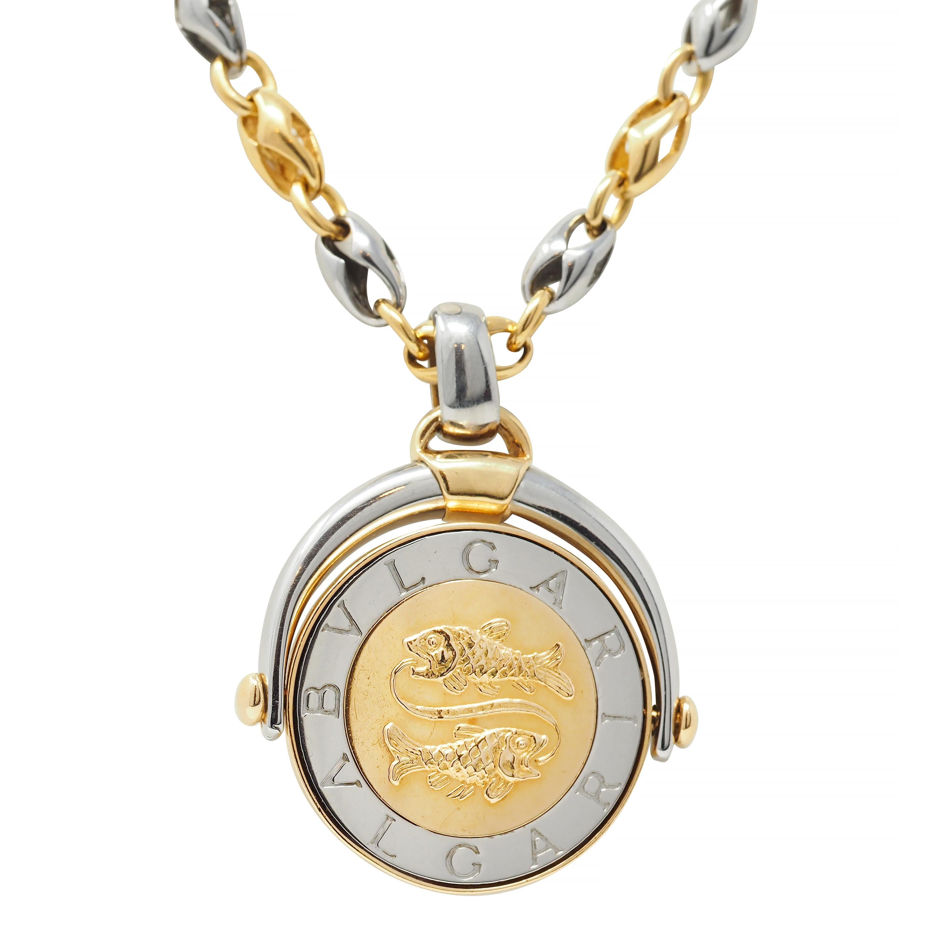 Comprised of a stylized yellow gold and stainless steel mariner link chain suspending a round disk pendant 
Centering a raised two fish motif for the astrological sign Pisces - with stainless steel logo engraved surround
Flips on an axis to reveal