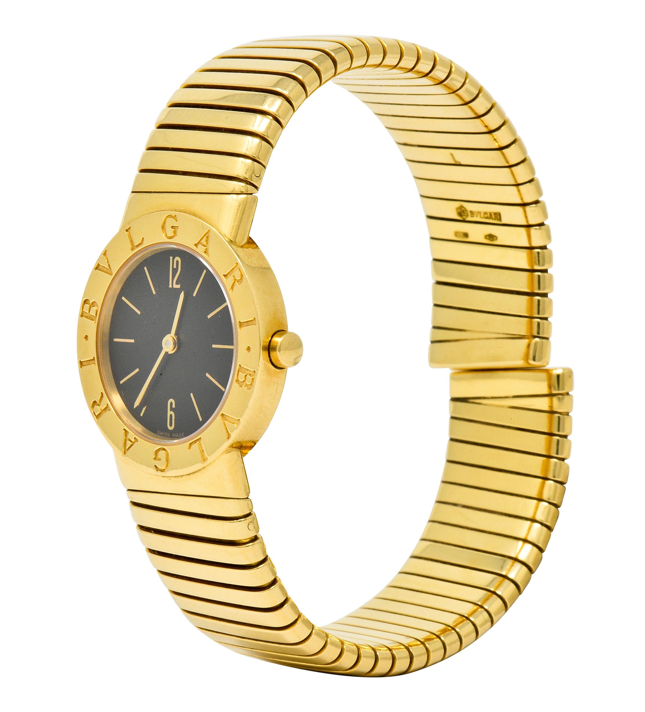 Flexible cuff style bracelet comprised of deeply ridged tubogas technology

Centering a sapphire crystal cover over a black watch face accented by gold hands and numerical markers

With a polished gold surround deeply engraved BVLGARI, twice