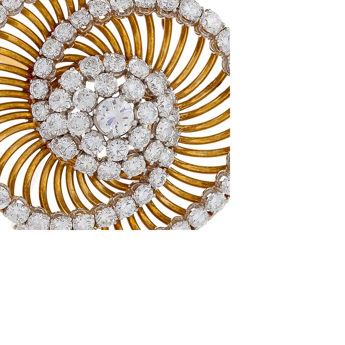 This intriguing brooch by Bulgari is set with six-and-a-half carats of round brilliant-cut diamonds, platinum set on a mount of yellow gold wire work. The dynamic, swirling form with intersecting arcs is designed as a pair of interlocking spirals