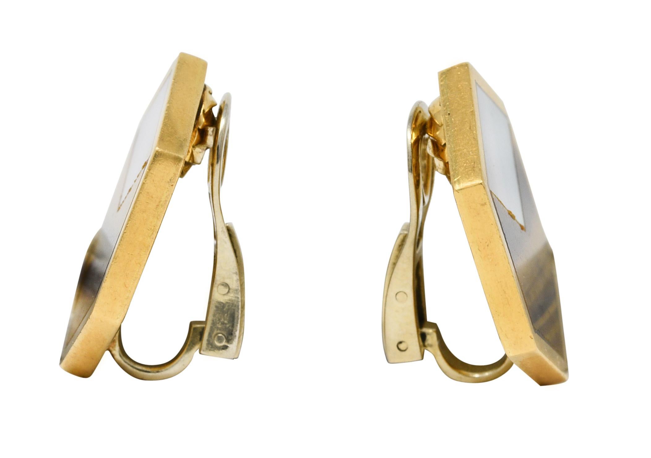 Designed as hexagon shaped forms centering inlaid tiger's eye quartz and mother-of-pearl. Tiger's eye is opaque with brown to yellowish orange banded color and strong chatoyancy. Mother-of-pearl is opaque white in body color with strong iridescence.