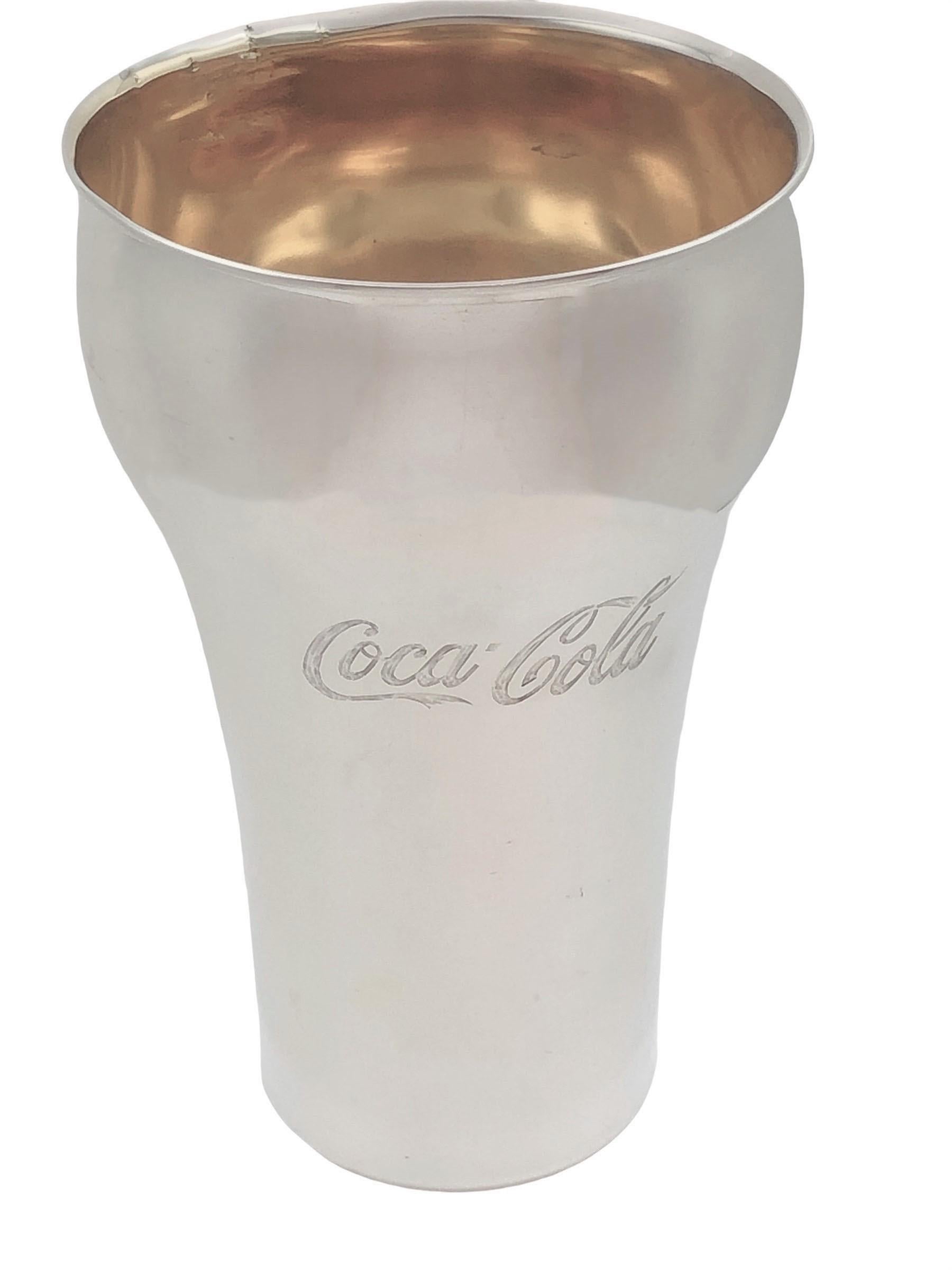 Circa 1980 Bulgari Presentation cup to Coca-Cola Executives Italy, in the form of the iconic Coca-cola shaped Drinking Glass with the Coca-Cola logo on both sides, Sterling Silver with a Gold wash interior, measuring 5 1/2 inches in height. Comes in