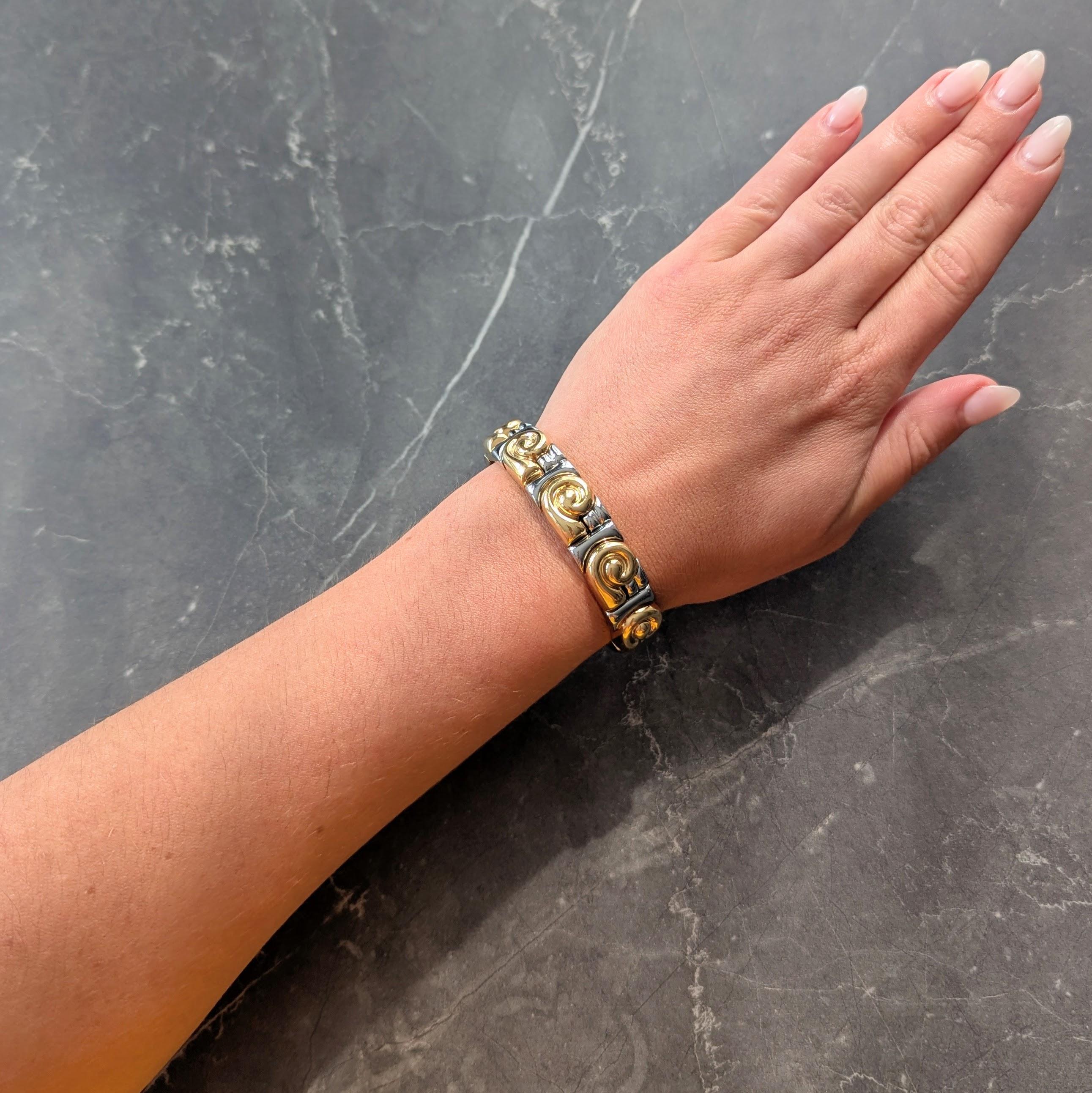 Composé de segments géométriques flexibles en or jaune et en acier inoxydable.
Avec des motifs tourbillonnaires en or jaune rainurés et des entourages géométriques en acier.
Avec une finition polie et des bornes ouvertes
Estampillé avec des marques