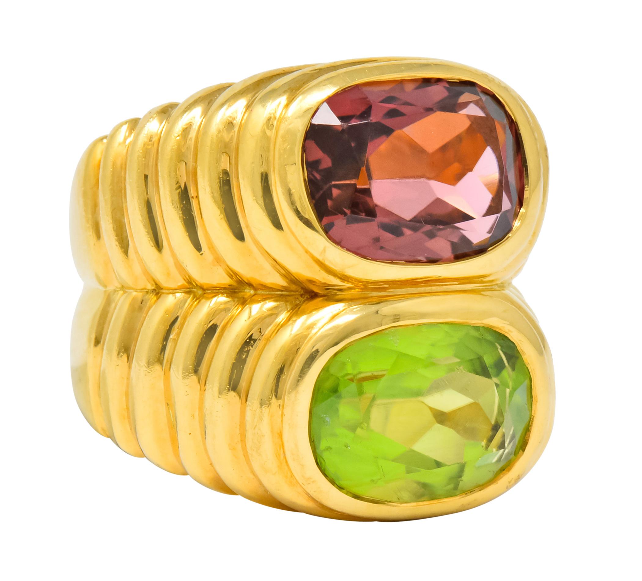 Ring designed as two deeply ridged bands stacked on top of one another, fused

One is bezel set with an oval mixed cut peridot weighing approximately 3.10 carats, transparent and yellowish-green

The other is bezel set with an oval mixed cut
