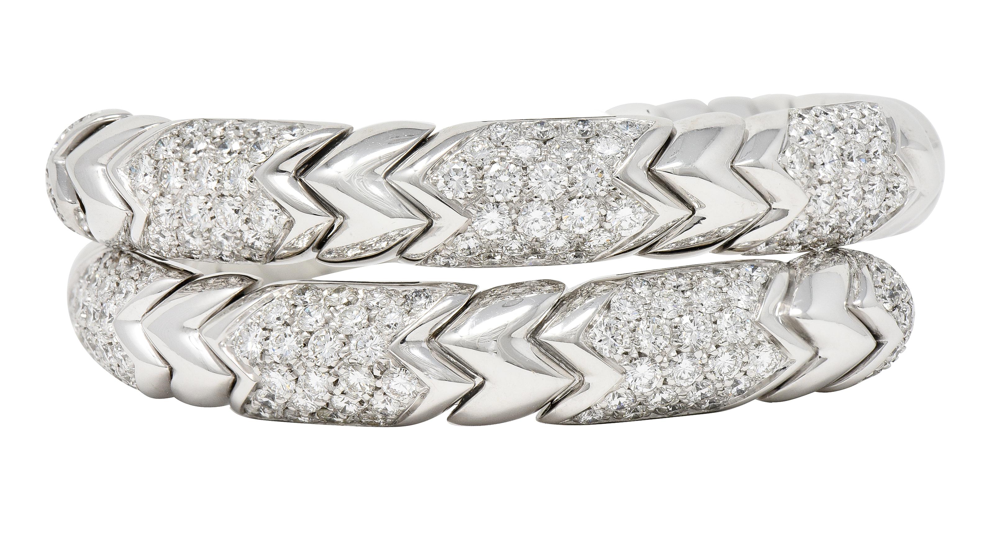 Designed as a flexible tubogas style wrap bracelet comprised of 'Spiga' motif zigzag segments. Featuring rounded terminals with round brilliant cut diamonds in pavéd segments. Weighing approximately 6.50 carats total - F/G color with VS clarity.