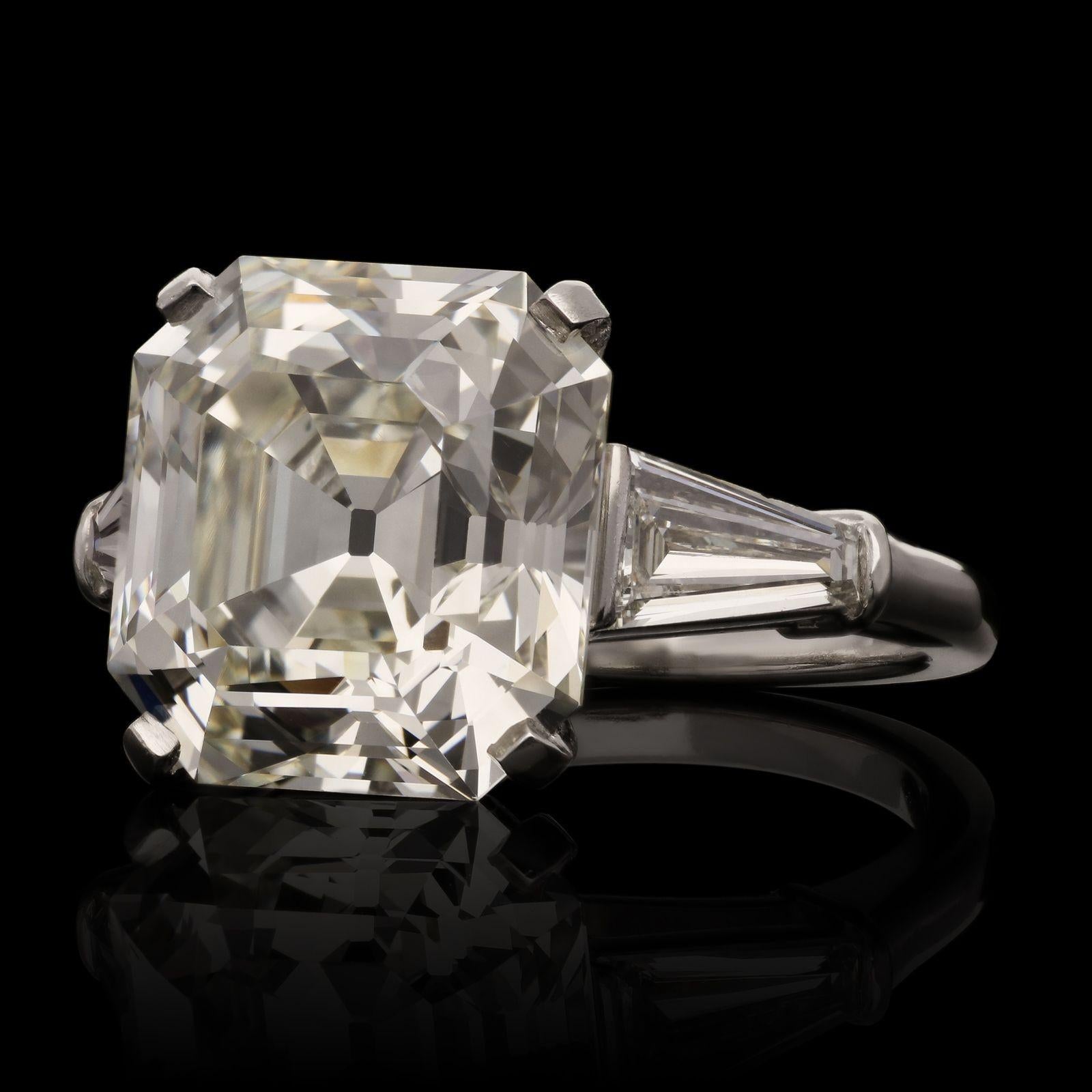A stunning diamond and platinum ring by Bulgari c.1960s, set with a bright and lively Asscher cut diamond weighing 8.38ct and of K colour and VS1 clarity, corner claw set to a simple double bar gallery, between tapered baguette diamond shoulders,