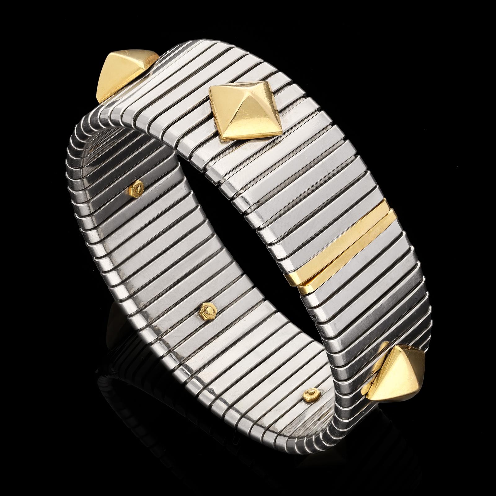 Description
A gold and steel Tubogas cuff bracelet by Bulgari c.1990s, the bracelet of flexible sprung design in stainless steel with straight edged opening to the centre back and with the iconic Tubogas slanted linear pattern, applied to the front