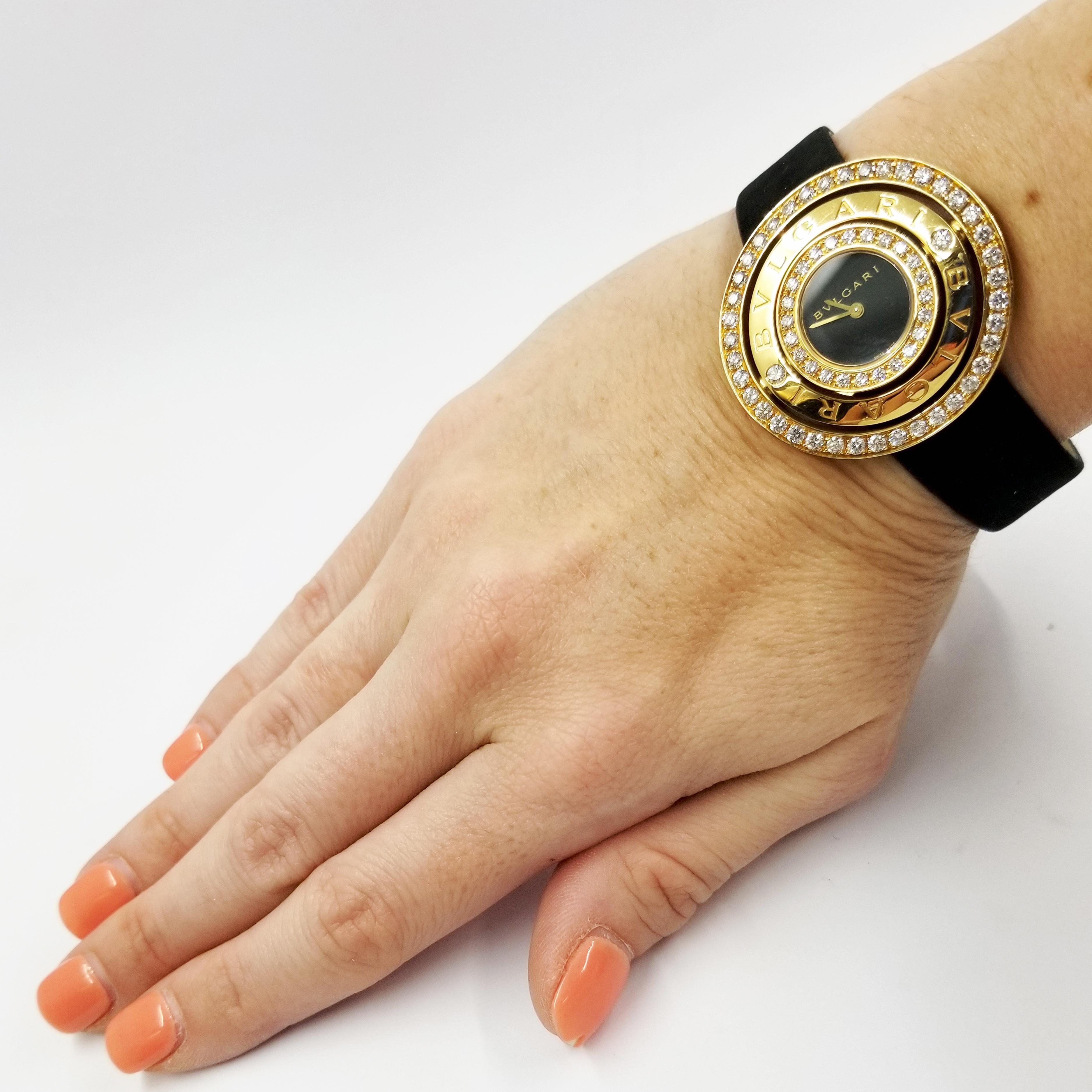 18 Karat Yellow Gold Quartz Watch from Bulgari. Original retail price is $25,900. The battery operated timepiece features a 36mm case comprised of three concentric rings around the black dial. The case contains 64 round brilliant diamonds totaling
