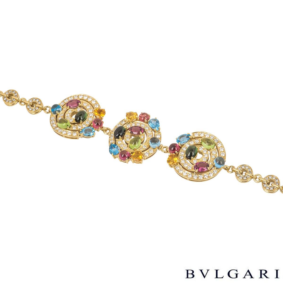 An alluring 18k yellow gold diamond and multi-gemstone bracelet by Bvlgari from the Astrale collection. The bracelet features 3 open work circular motifs in a floral design set with pave round brilliant cut diamonds with blue topaz, tourmaline,