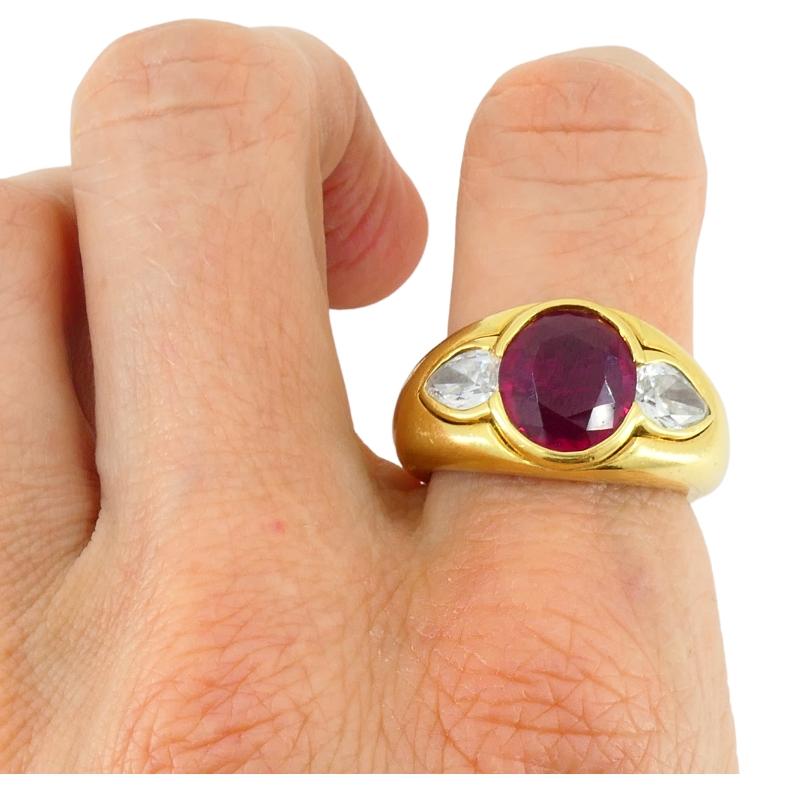 A vintage Bulgari band ring made 18k gold, featuring cabochon ruby and diamonds. The ring comes with the AGL and GIA certificates. 
The band has a smooth and substantial presence with a slightly domed shape. At the center sits an oval cut ruby,