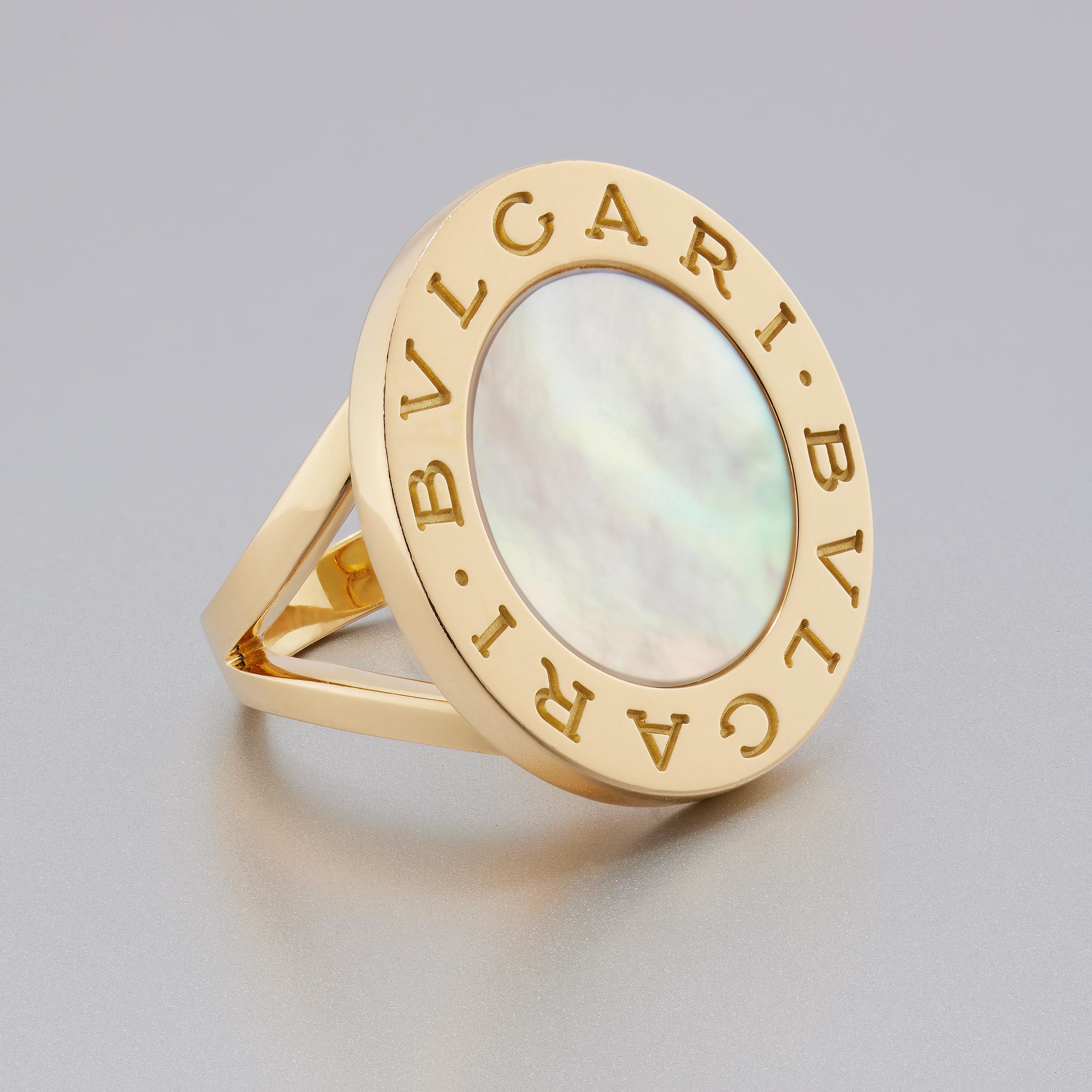 From iconic Bulgari comes this big, bold, and stylish ring featuring a mother-of-pearl center disk inlaid in luminous 18 karat yellow gold setting. Part of the Bvlgari Bvlgari collection, the ring features Bulgari’s trademark double logo engraved