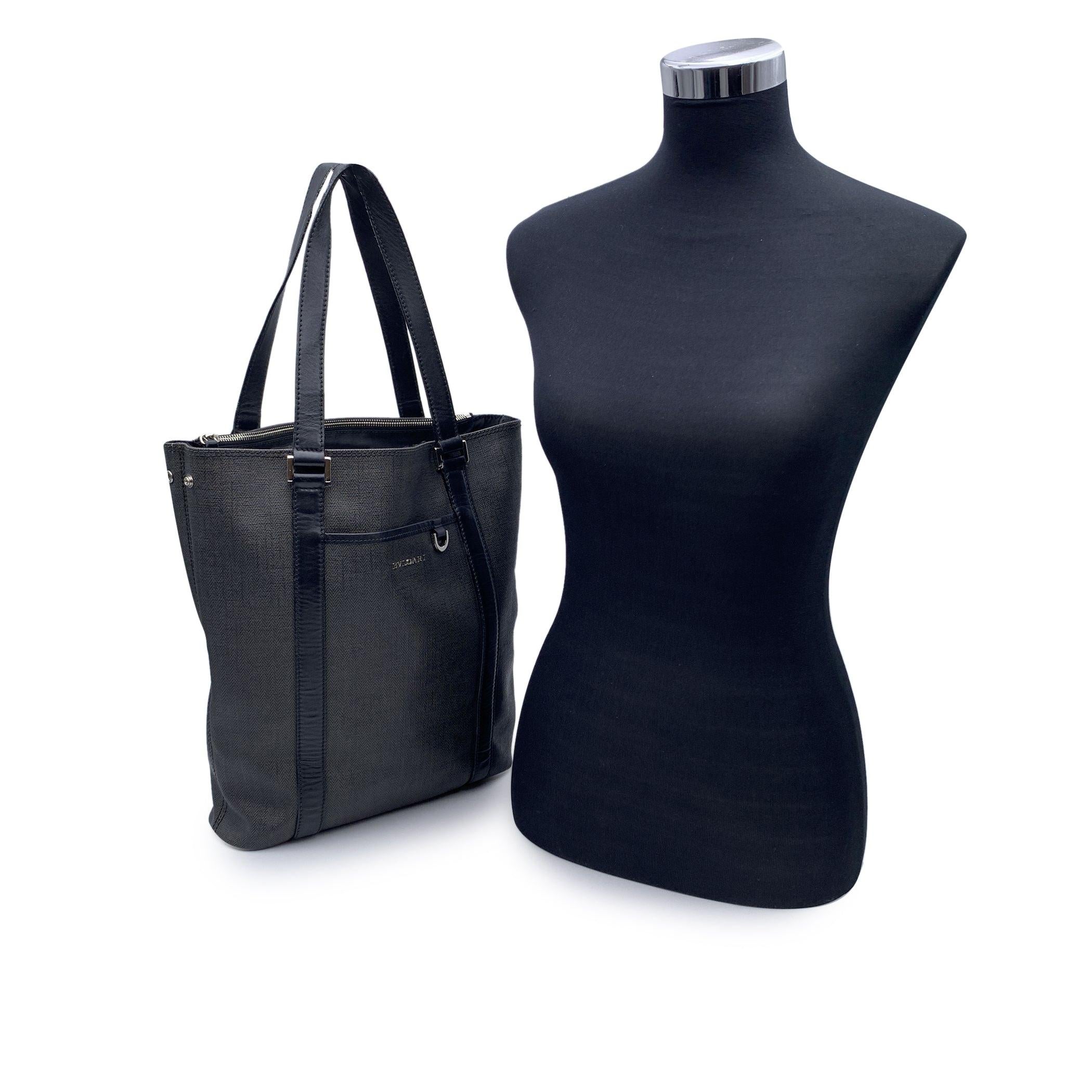 Bvlgari Bulgari unisex tote bag, crafted in greu canvas with black leather trim and shoulder straps. Silver metal BVLGARI lettering on the front. Small pocket with D ring on the front. Open top. 1 hidden zip compartment. Blck fabric lining. 1 side