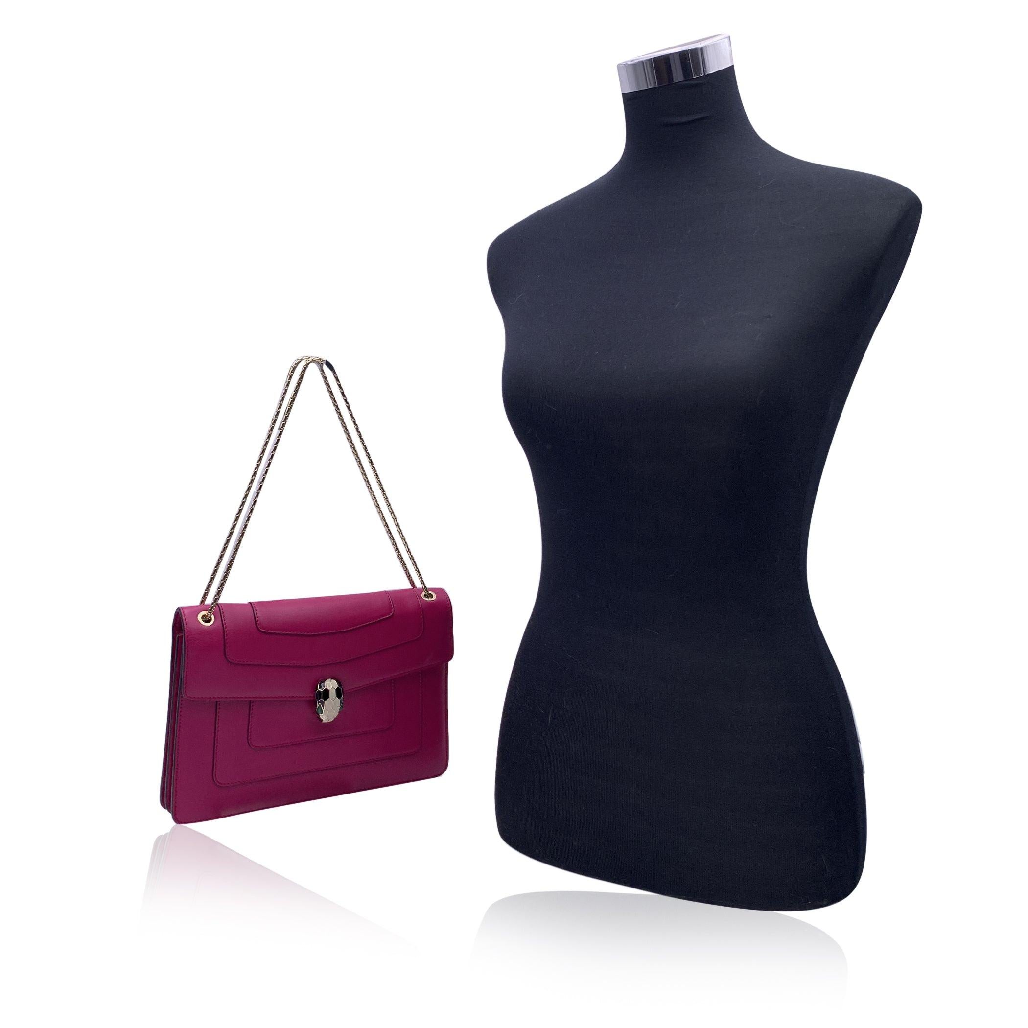 Elegant Bulgari 'Serpenti Forever' Shoulder bag. Crafted in pink leather , it features a beautiful Serpenti snake's head clasp on the front in gold metal, white and black enamel with green malachite eyes. Gold metal shoulder strap. Purple grosgrain