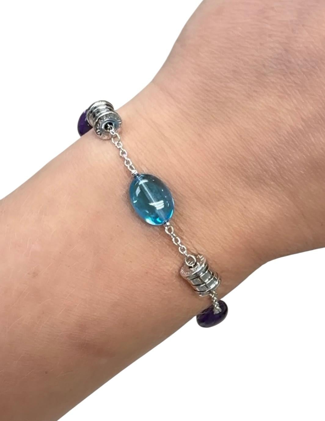 Dalla classica Collection B.zero1, questo bracciale contiene due perle ovali di topazio blu e due perle ovali di ametista, intervallate da tre barilotti tutti con l'incisione Bulgari. Il bracciale è regolabile in tre misure diverse e ogni chiusura a
