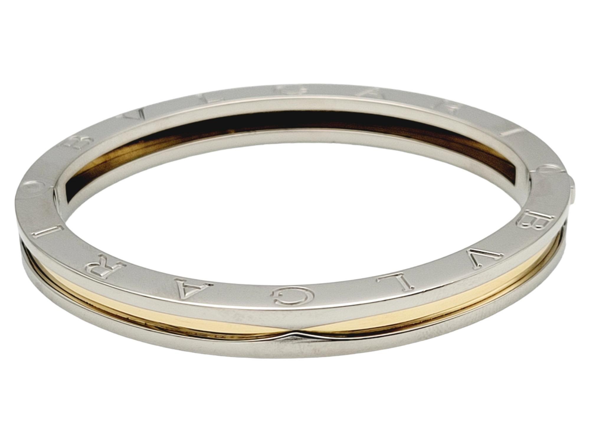 Presenting a stunning Bulgari B.ZERO1 Two-Tone 18-Karat Yellow Gold & Stainless Steel Bangle Bracelet, a true masterpiece of Italian craftsmanship. This exquisite piece showcases a seamless blend of 18-karat yellow gold and stainless steel, creating