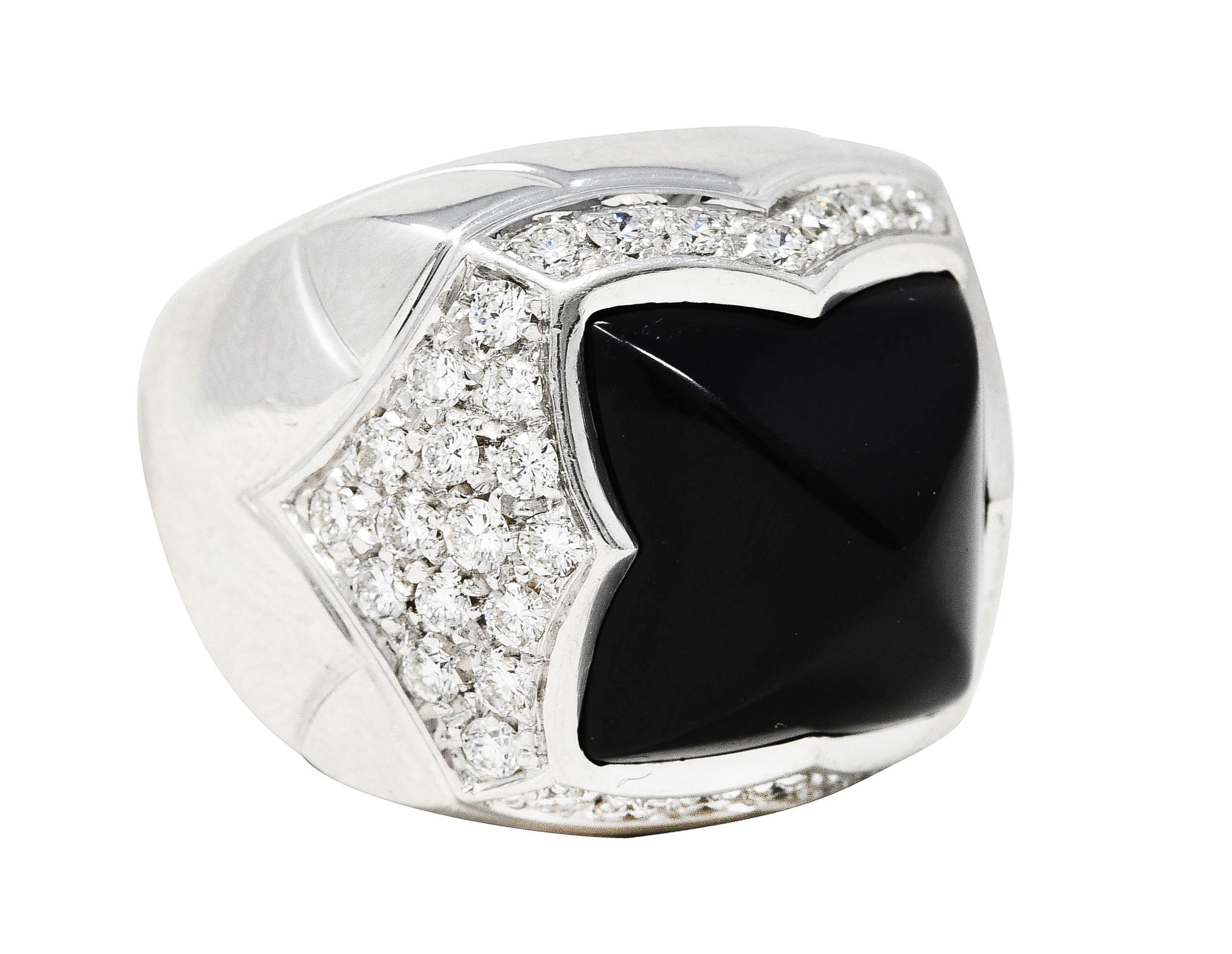 Ring is designed as a domed form with a quatrefoil motif mounting. Centering pyramidally carved onyx and grooved chevron motif shoulders. Accented by round brilliant cut diamonds pavé set in surround. Weighing approximately 1.38 carat total - G/H in