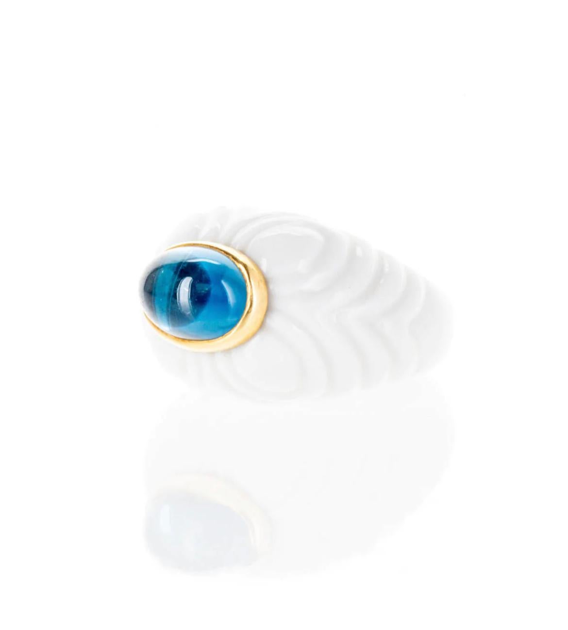 A beautiful ring in 18kt yellow gold and white porcelain, set with one natural Blue Topaz Cabochon cut. Signed Bulgari, from the “Chandra” collection, Made in Italy, circa 1990.
Designed as a series of part textured porcelain spheres depicting a