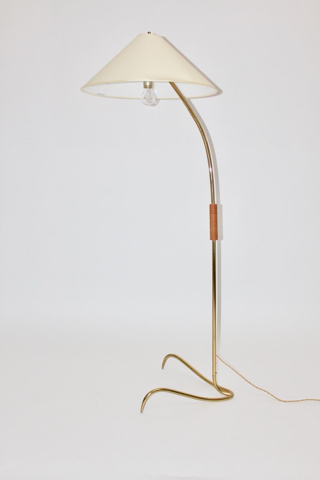 Mid century modern vintage brass floor lamp by Rupert Nikoll 1950s, Vienna, which appears elegant.
This beautiful floor lamp shows a wooden handle, while the stem was made of brass.

A renewed cream white fabric lamp shade is sitting on the top.
The