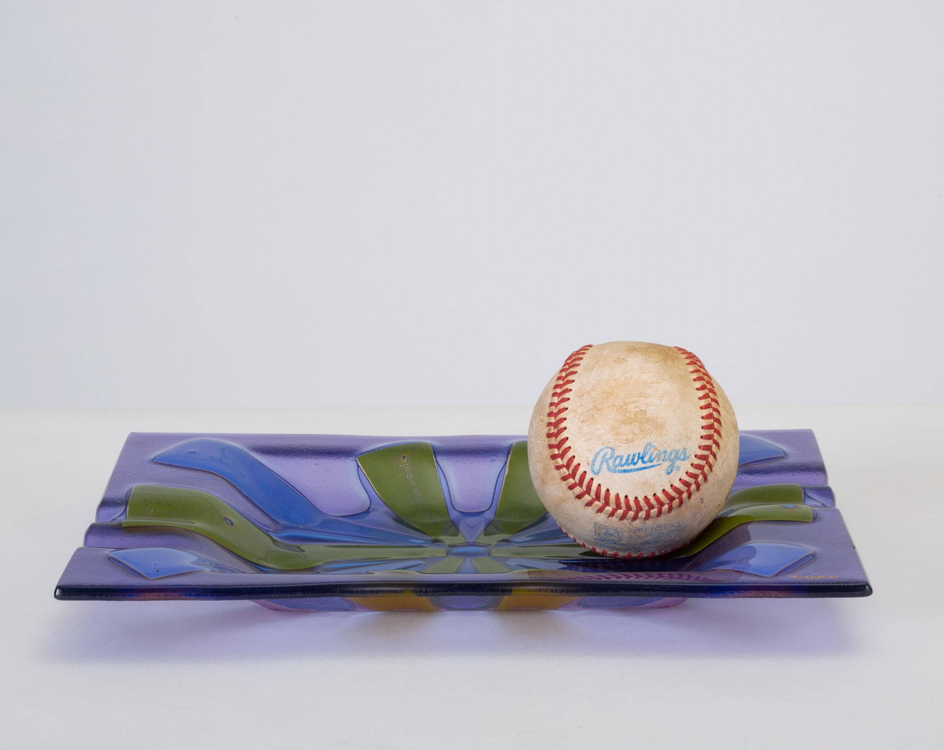 A fused-glass ashtray produced for Higgins by Dearborn glass in the mid-1950s to early 1960s. The pattern, called “Tortoiseshell” is created by sandwiching enameled glass panels of periwinkle blue and avocado green between tinted lavender glass