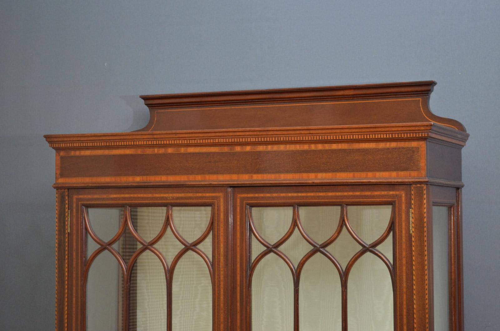 Sn4053, an elegant Edwardian inlaid display cabinet in mahogany, having shaped upstand (optional) and satinwood crossbanded frieze above a pair of glazed doors with inlaid panels, enclosing relined interior, all standing on tapering legs terminating