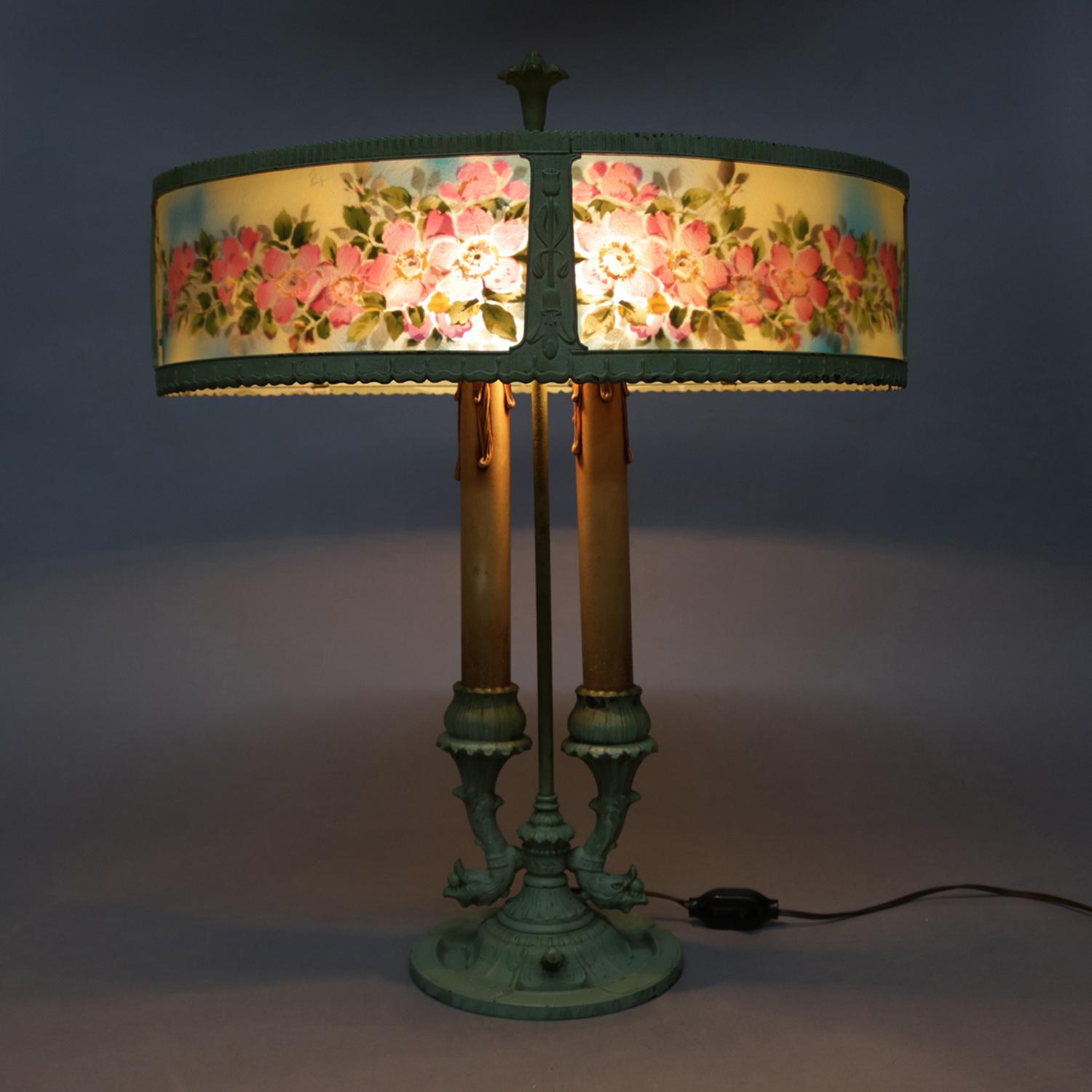 French Bouillotte table lamp by Rainaud Co. features rare form reverse painted oval shade with floral decoration over painted cast figural lamp having dolphins and two candle lights with gilt drips, signed on base, circa 1890.

Measures: 25