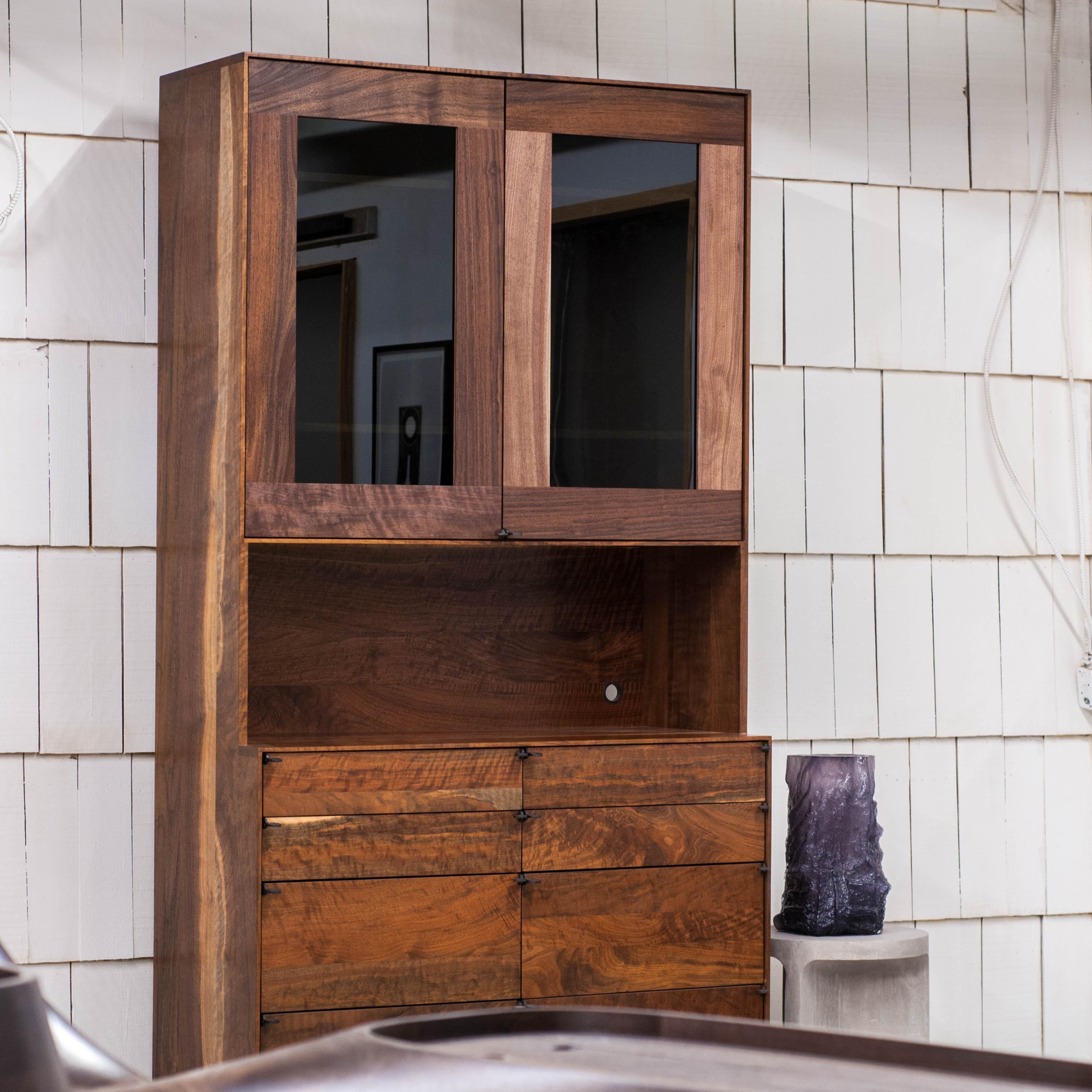 Curio cabinet constructed of Claro walnut, sourced from the Gibson Guitar factory. Blackened metal hardware. Chalice and camp style pulls. Minimal edge reveal with soft close hardware, dovetailed drawers, and height adjustable shelving. Options
