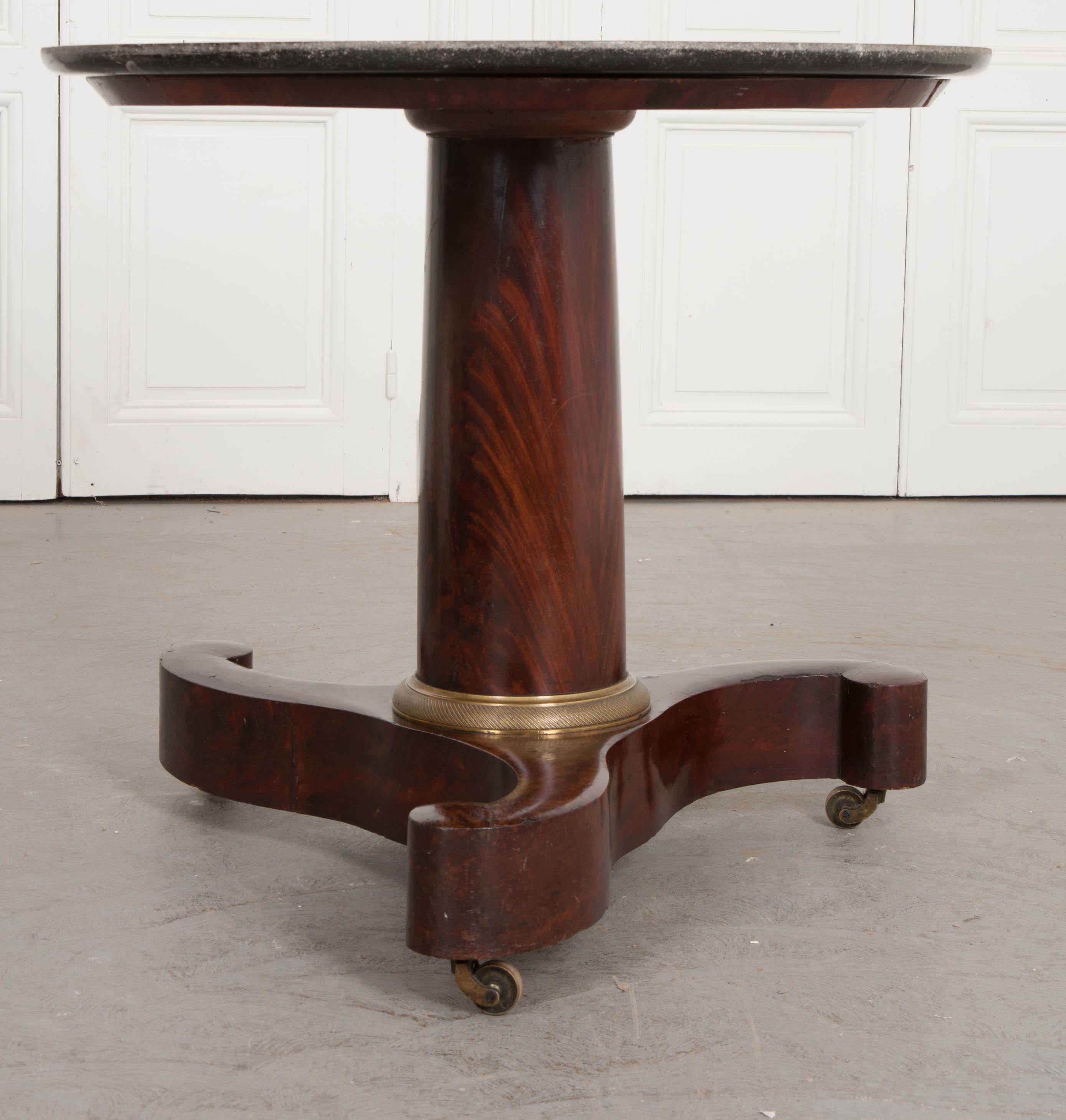 A handsome mahogany Empire pedestal table, made in France, circa 1870. The table has a round, black fossil marble top that is slightly welled and in fabulous antique condition. The top is supported by a thick pedestal that connects it to the styled