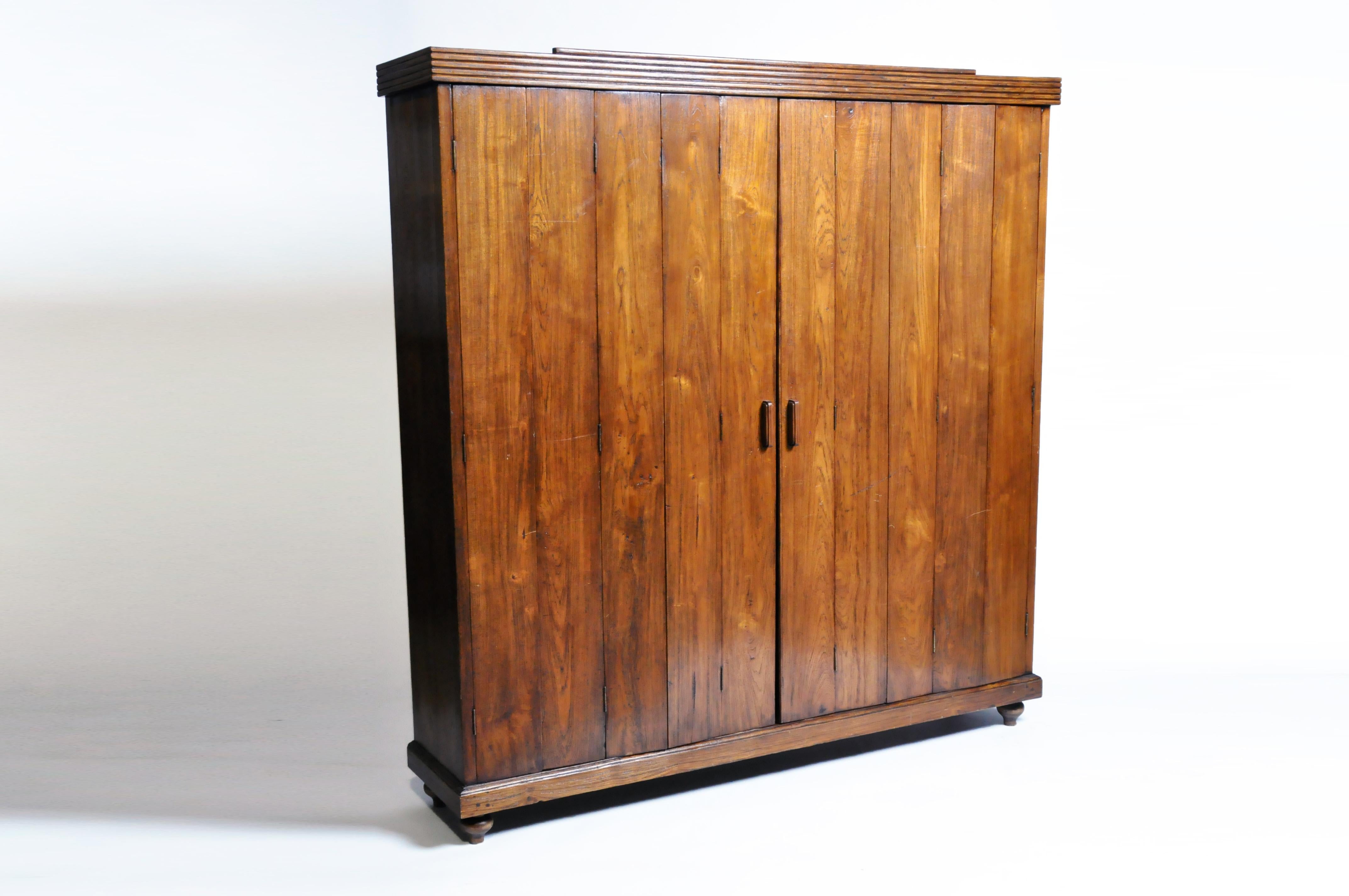 This handsome Art Deco cabinet is from Burma and was made from teak wood, circa 1940. This piece features three shelves and a pair of five-panel folding doors.